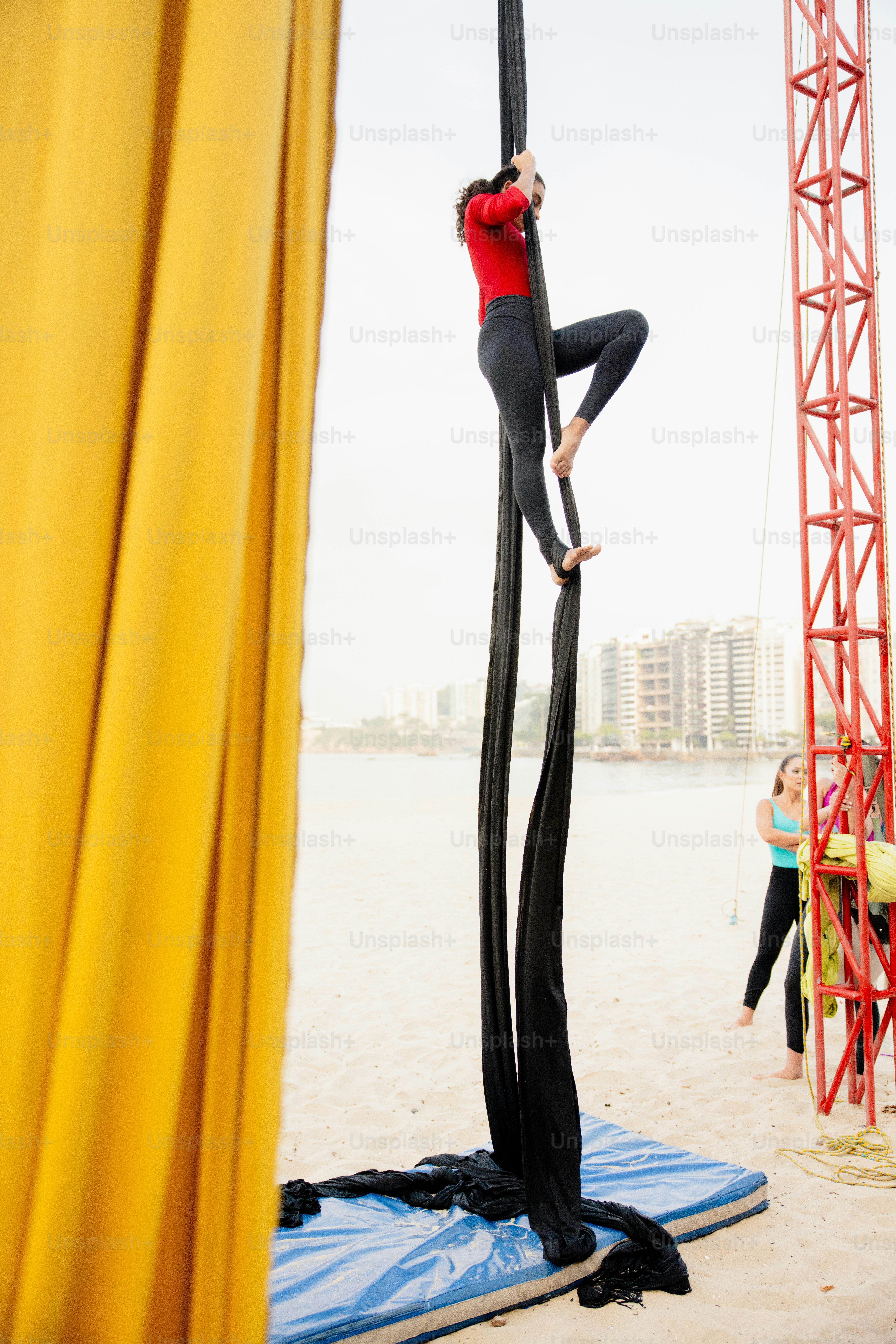 A woman standing on top of a pole on top of a beach