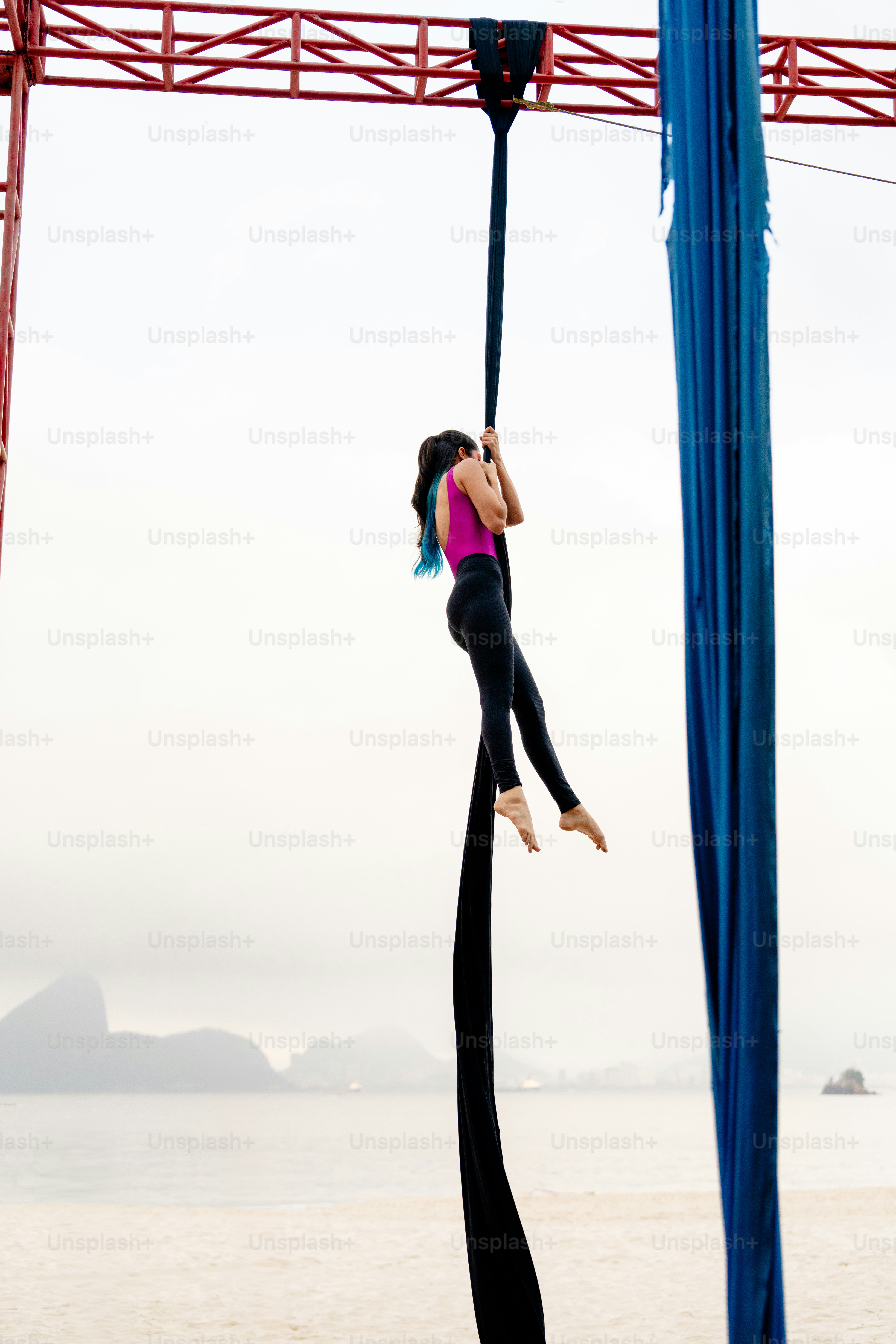 A woman is hanging upside down on a pole