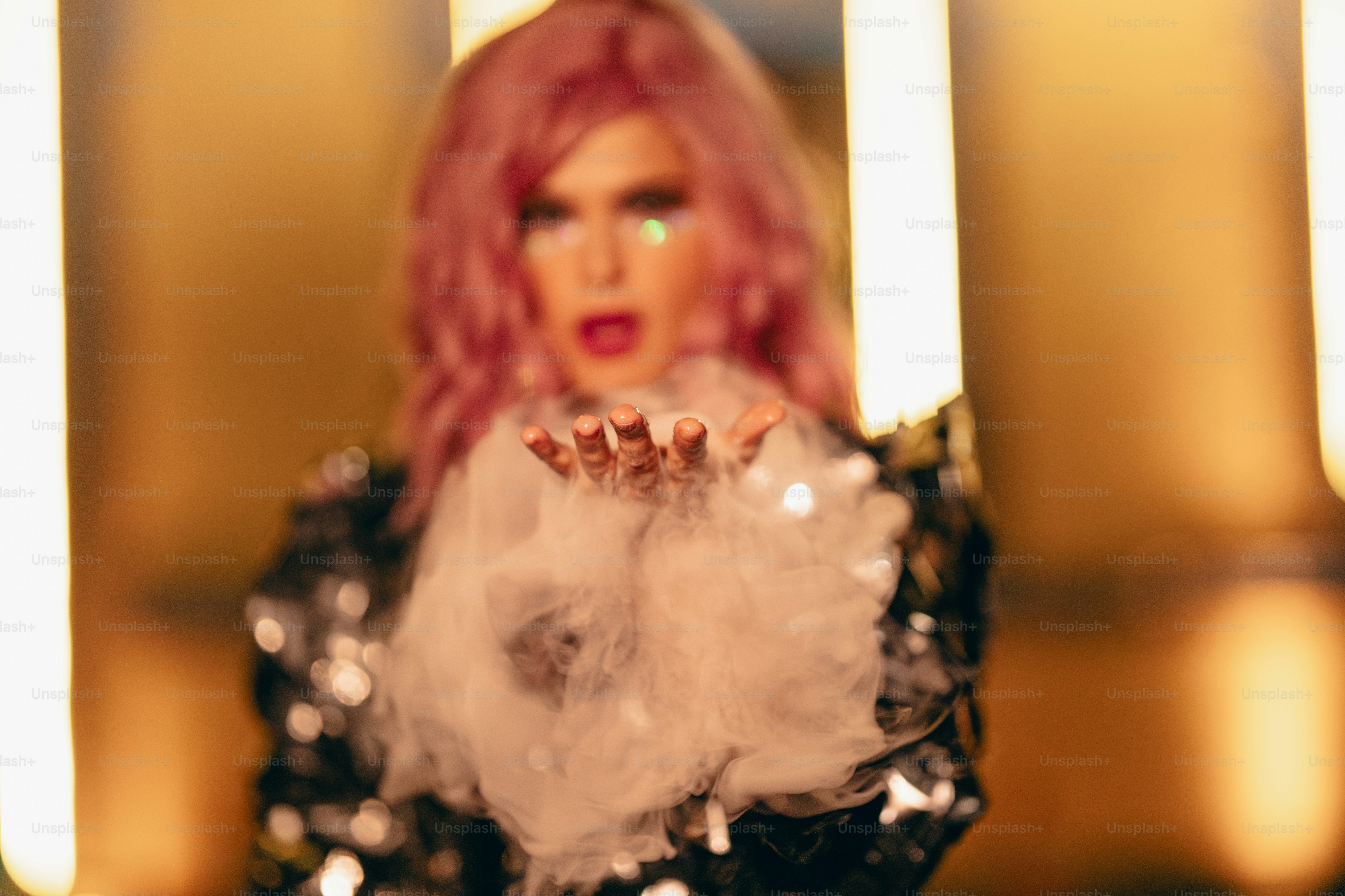 A woman with pink hair holding a cake