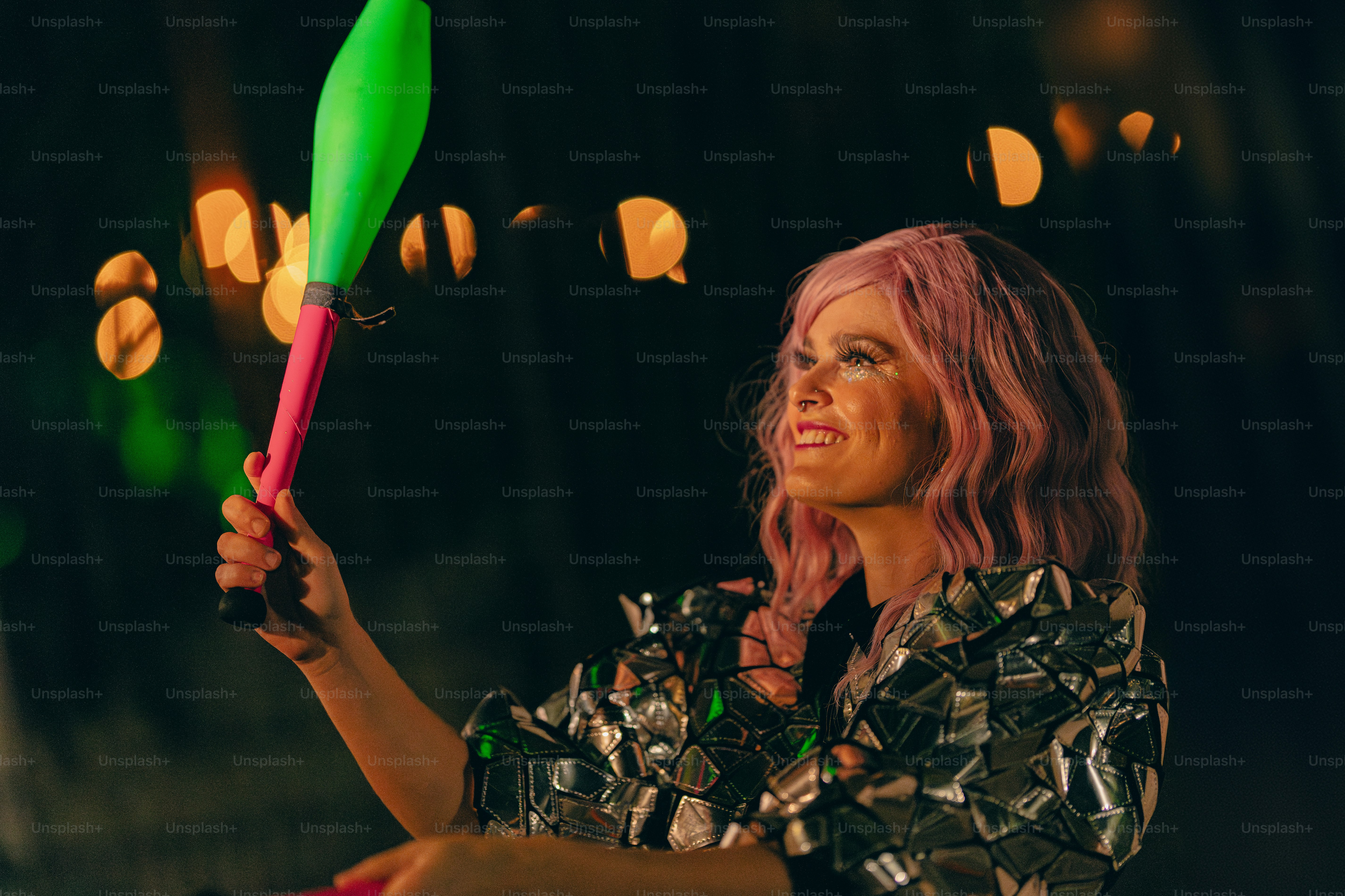 A woman with pink hair holding a green and pink umbrella