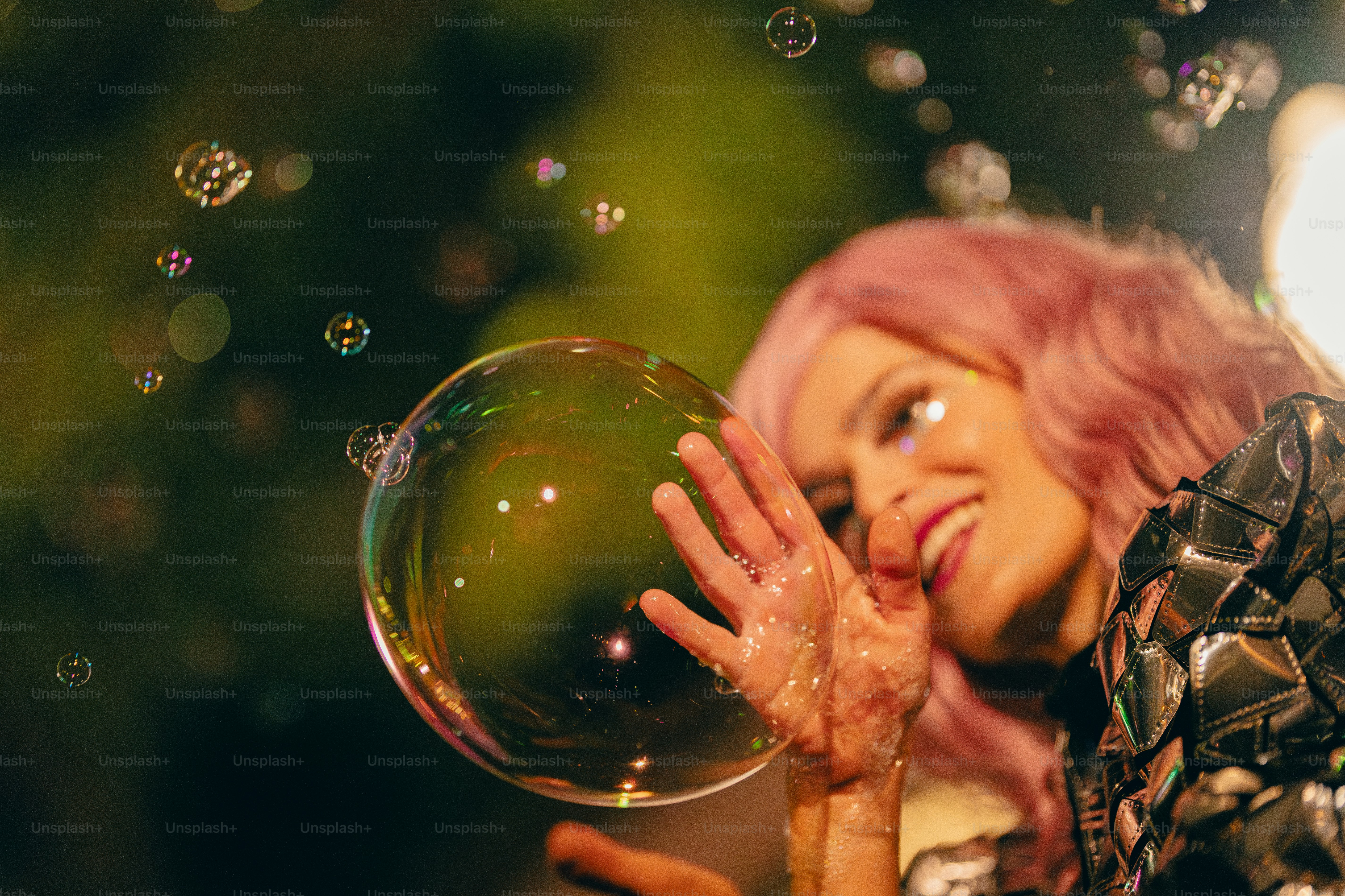 A woman with pink hair is blowing bubbles