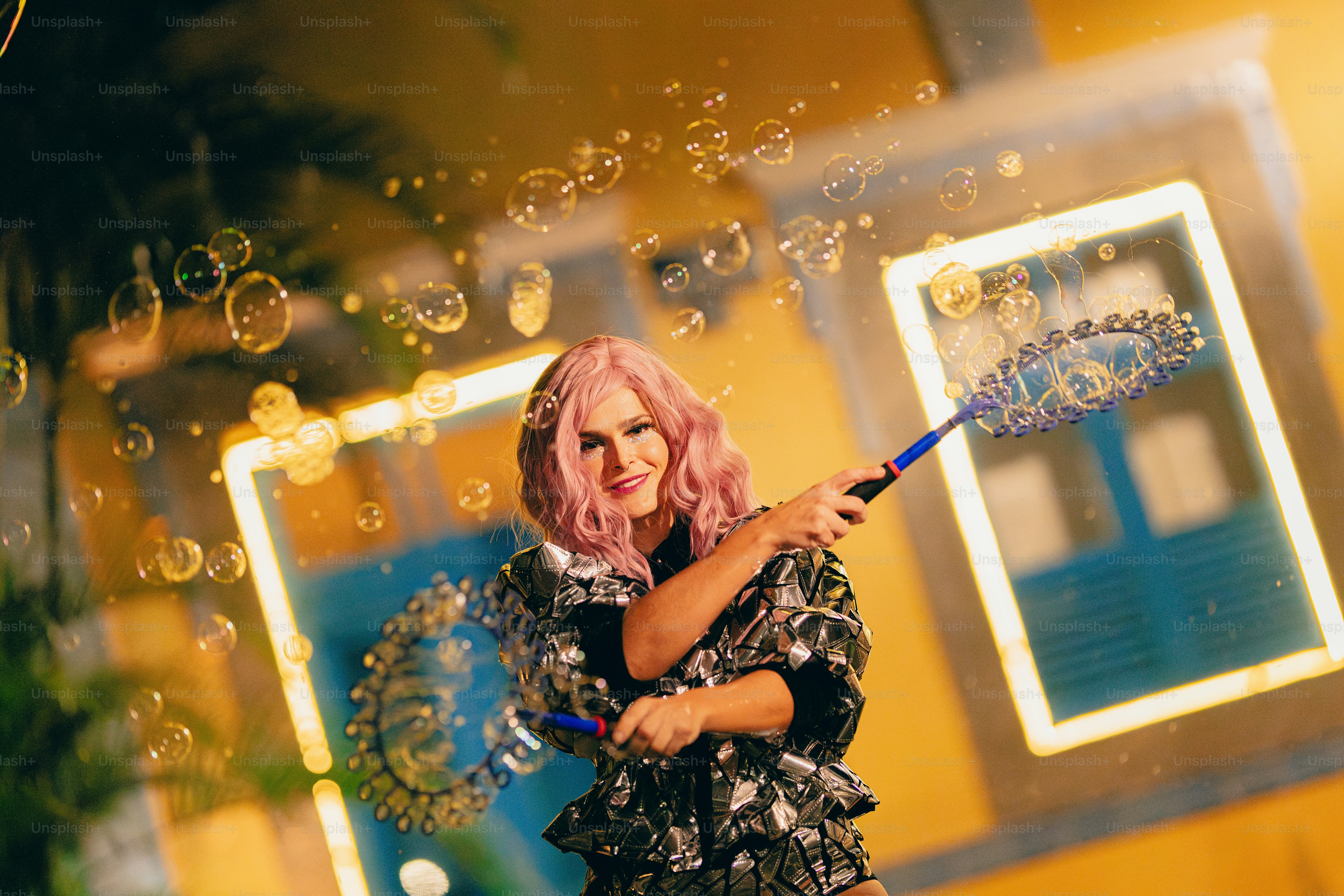 A woman with pink hair is blowing bubbles