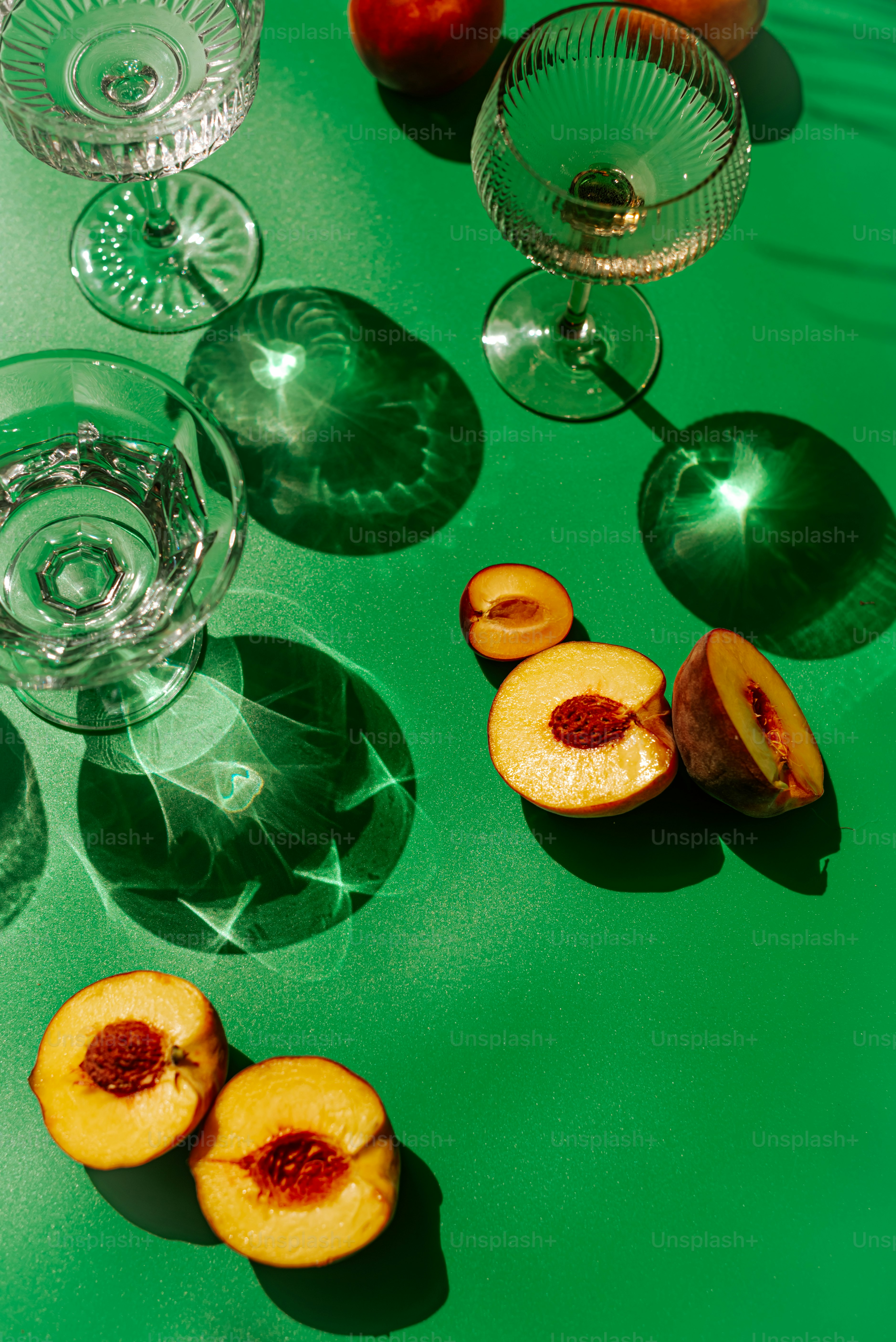 A green table topped with glasses and fruit