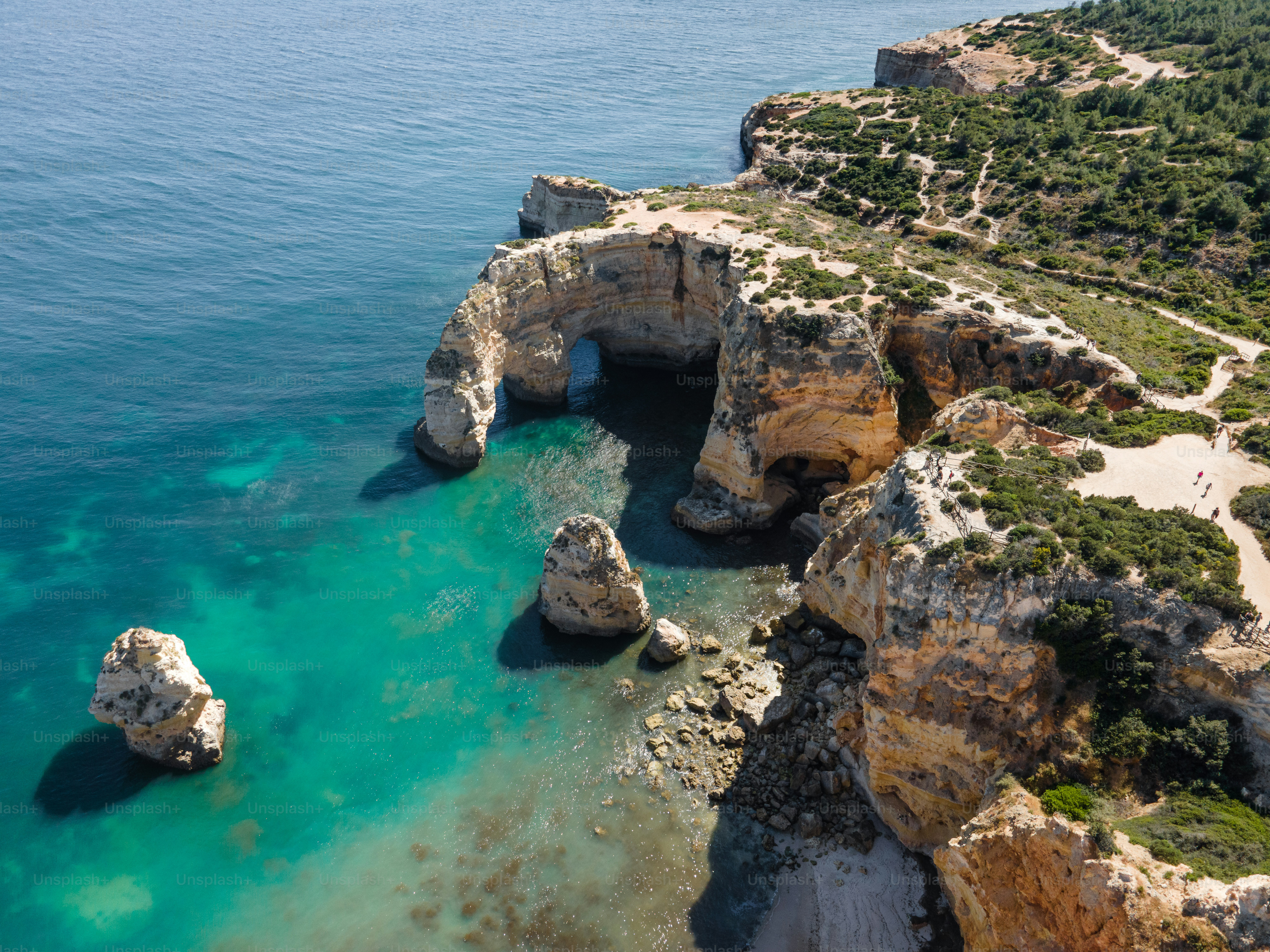 An aerial view of a rocky coastline with clear blue water