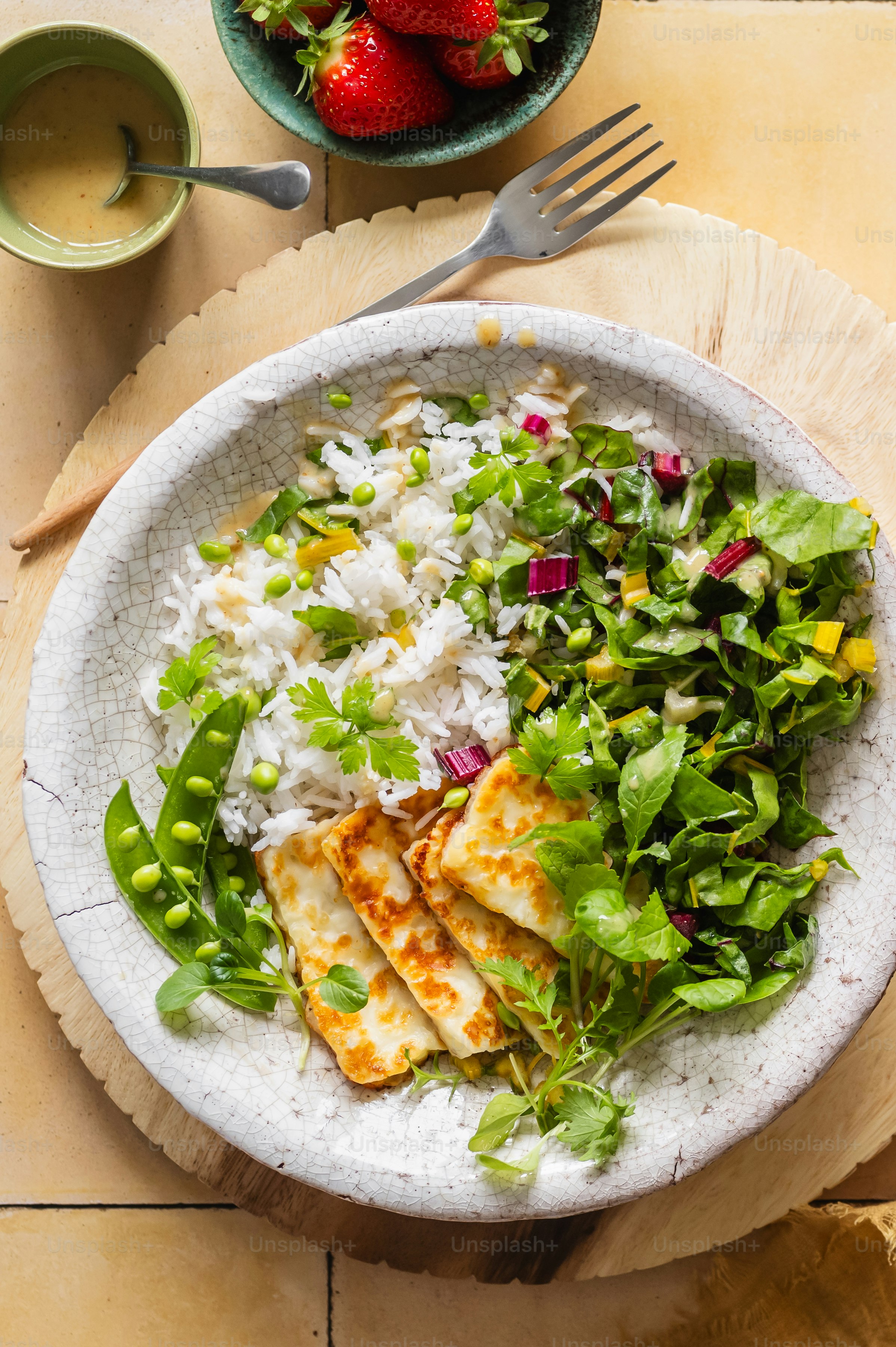 A plate of food with rice, salad, and strawberries