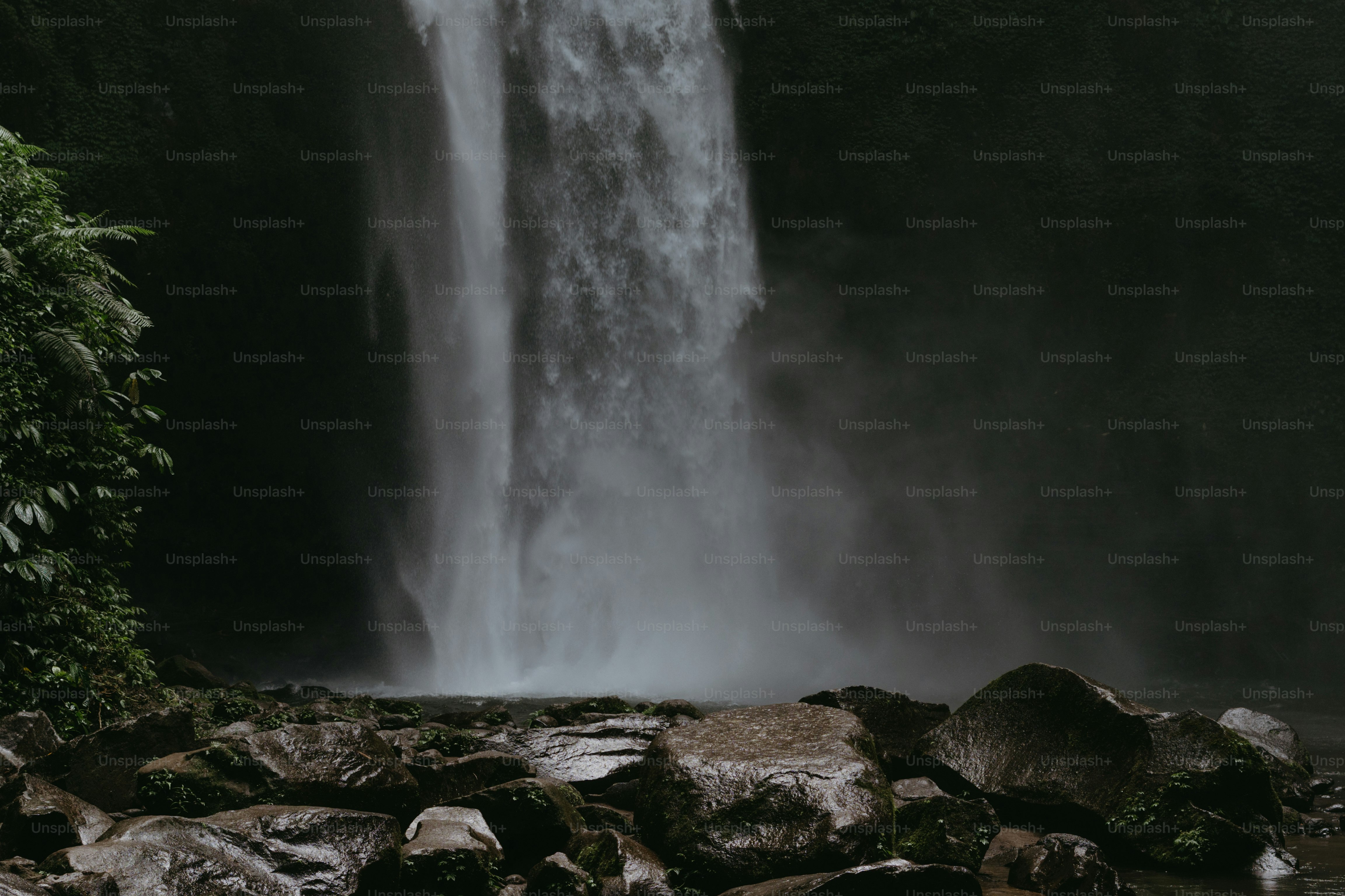 A large waterfall with a man standing in front of it