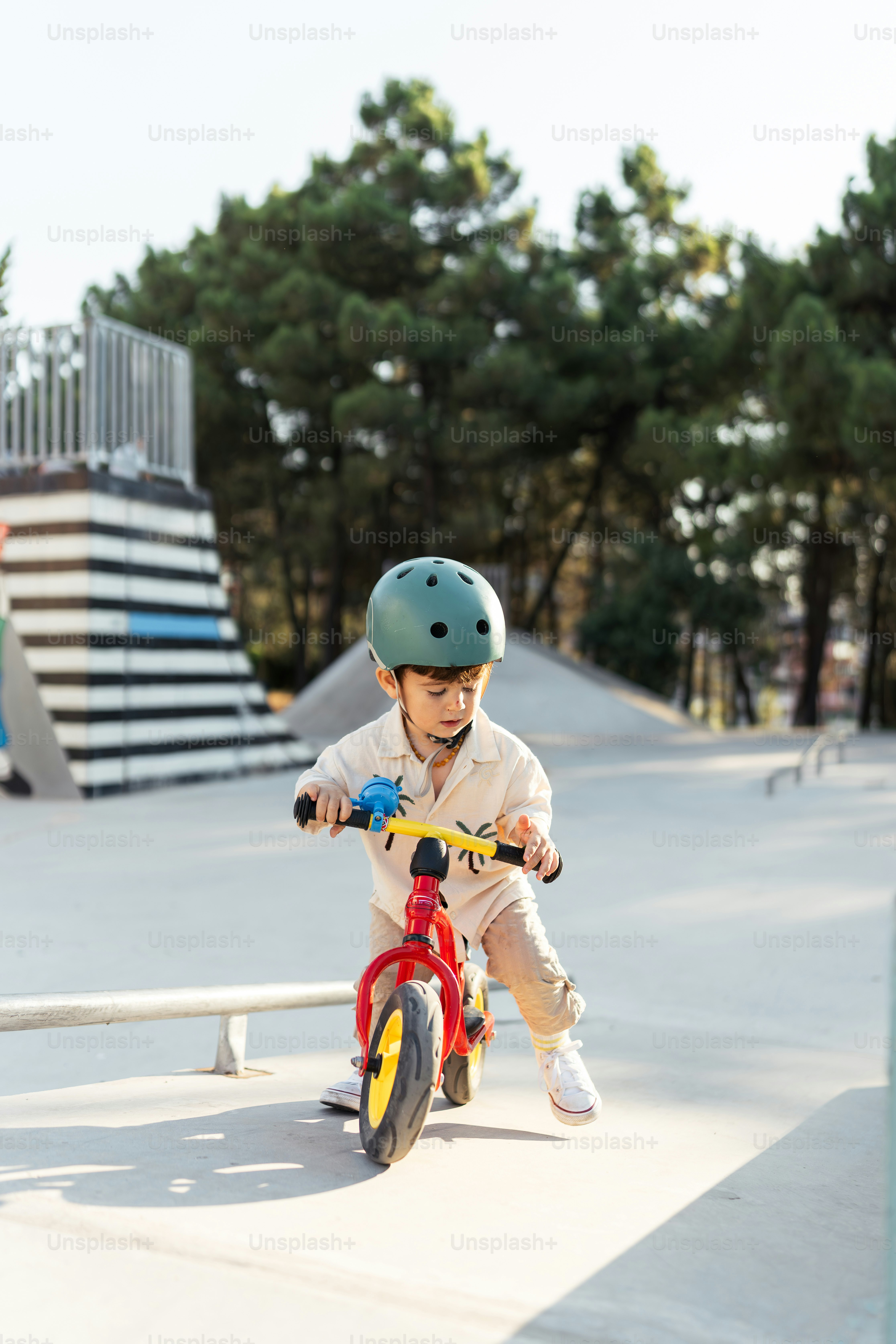 A young boy riding a red bike down a ramp