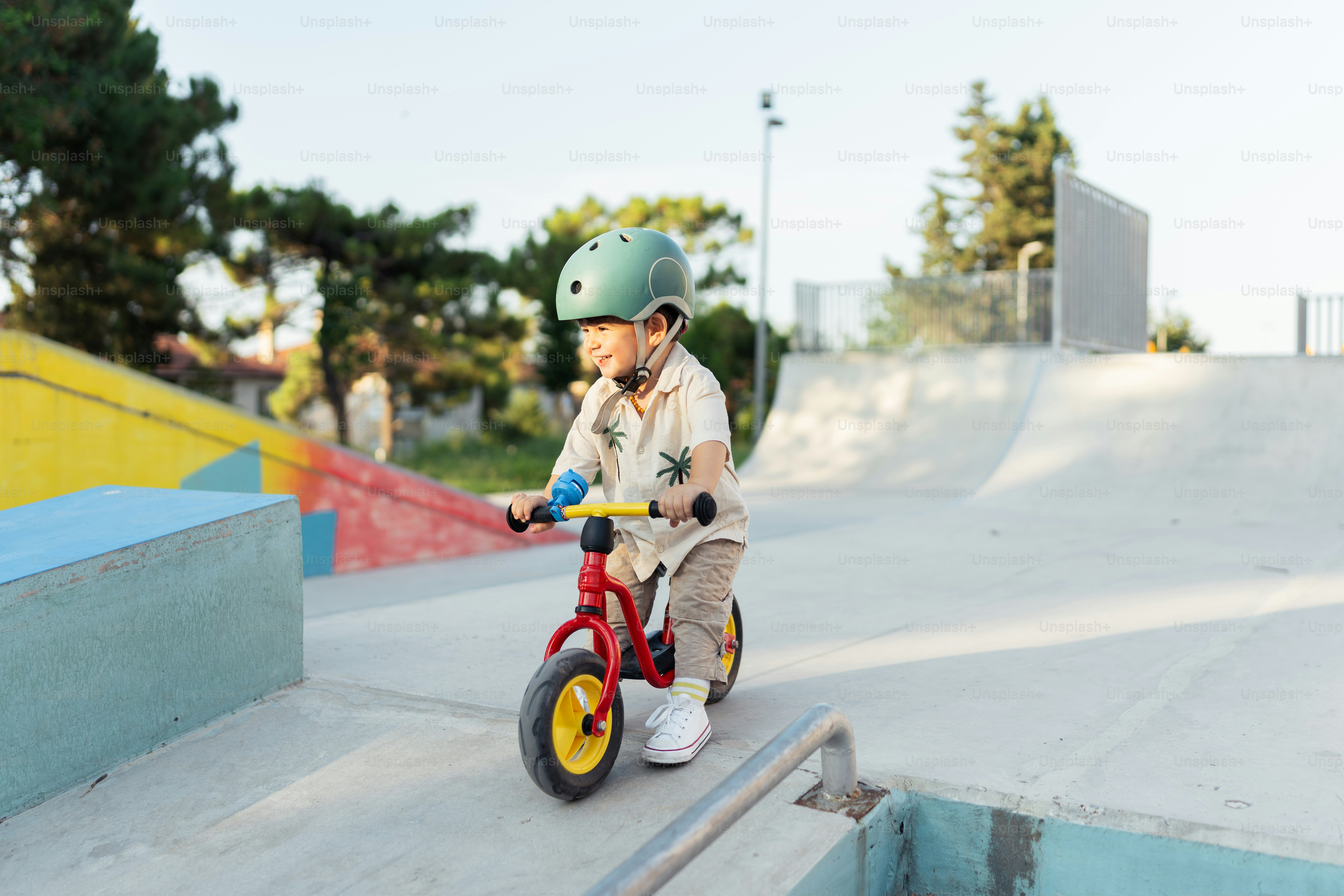 A young boy riding a red bike at a skate park