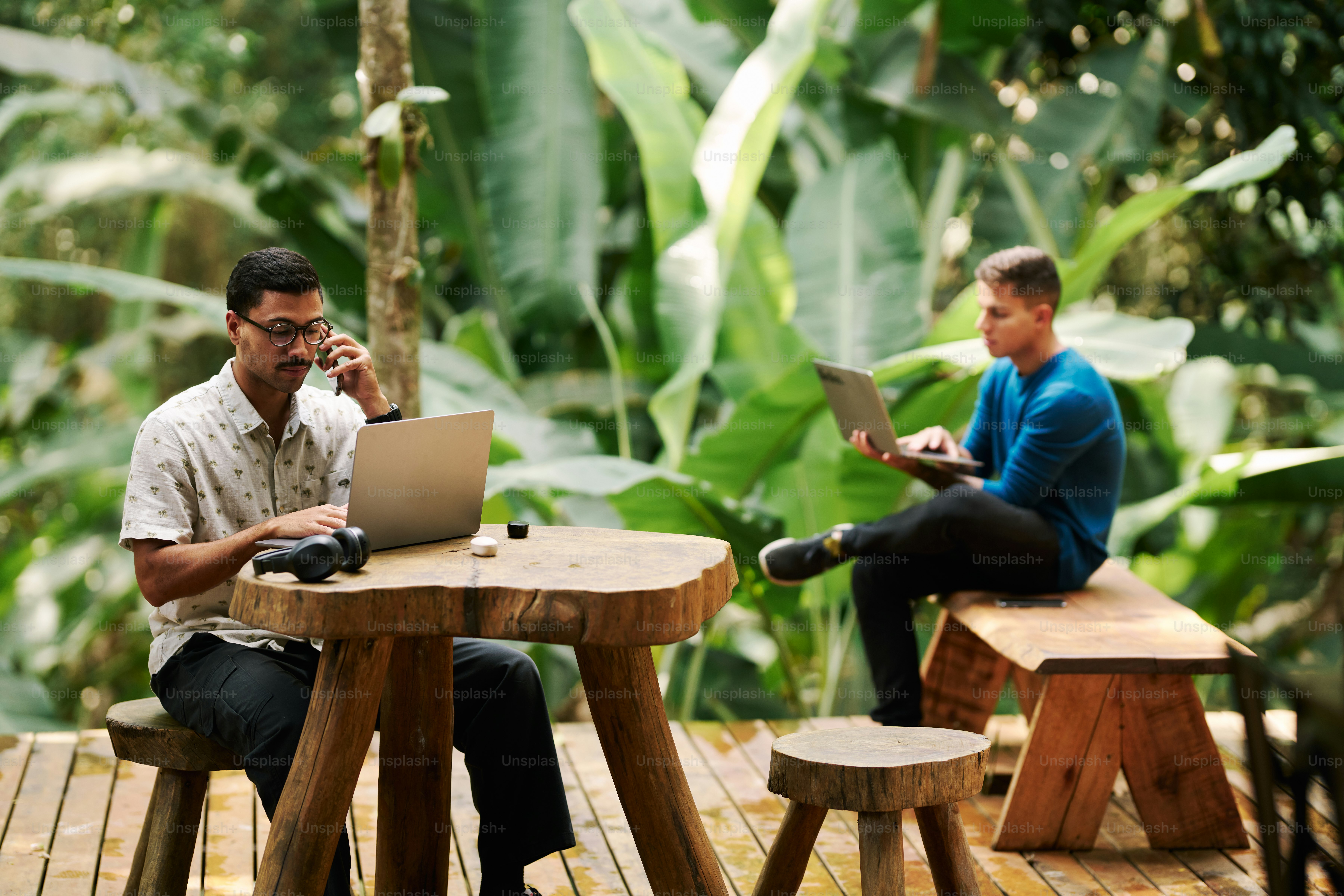 Two men sitting at a table with laptops