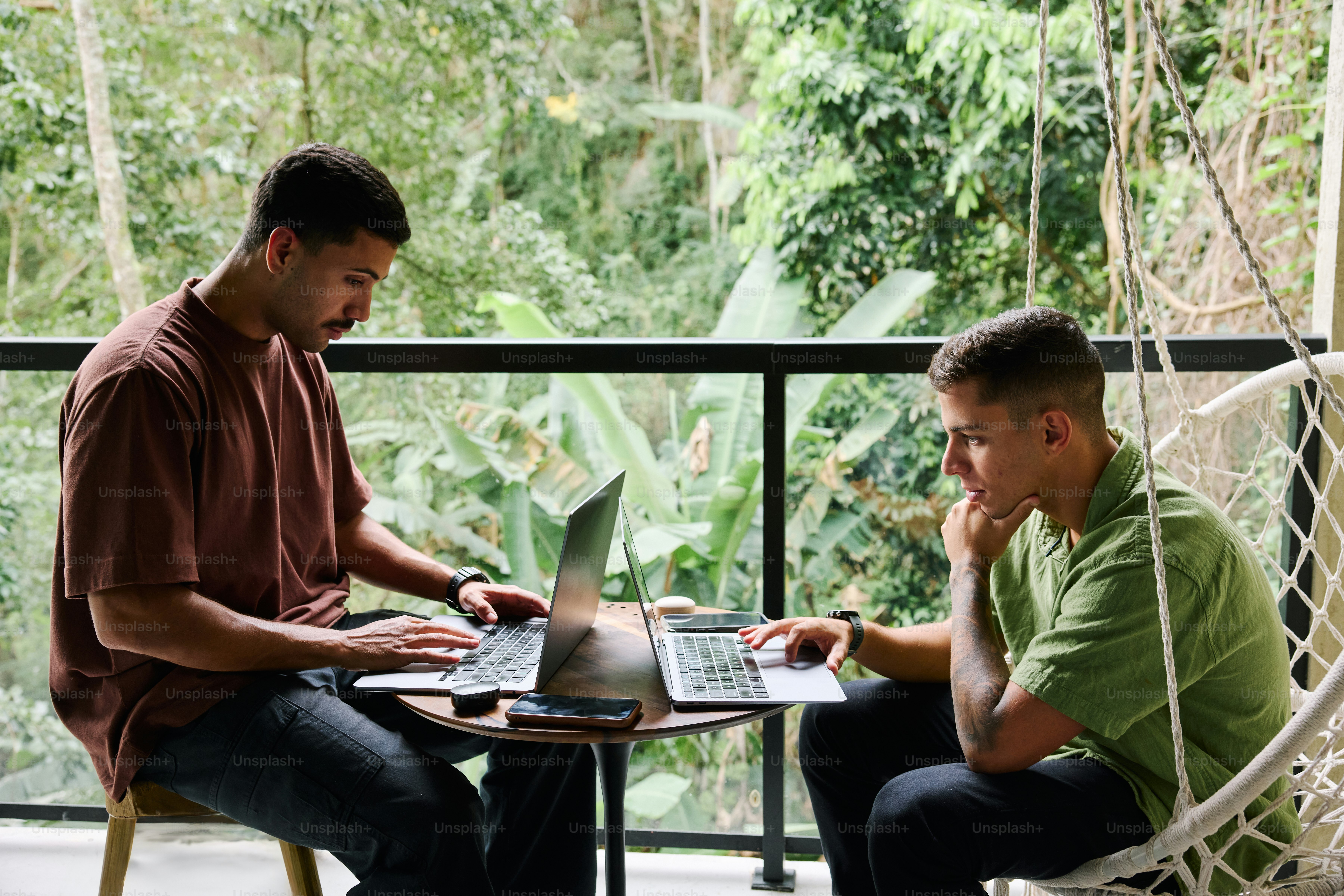 A couple of men sitting at a table with laptops