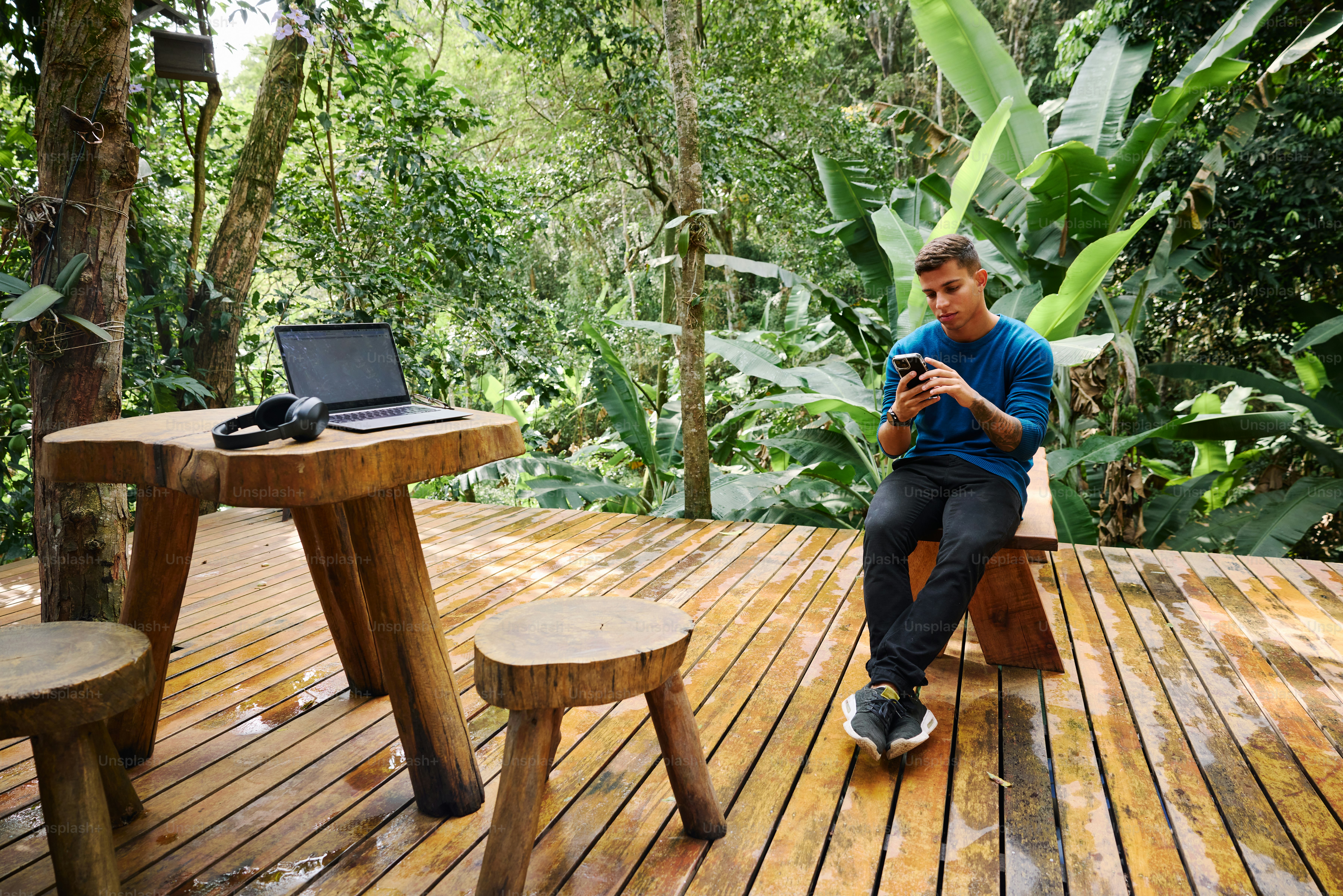 A man sitting on a wooden deck using a cell phone