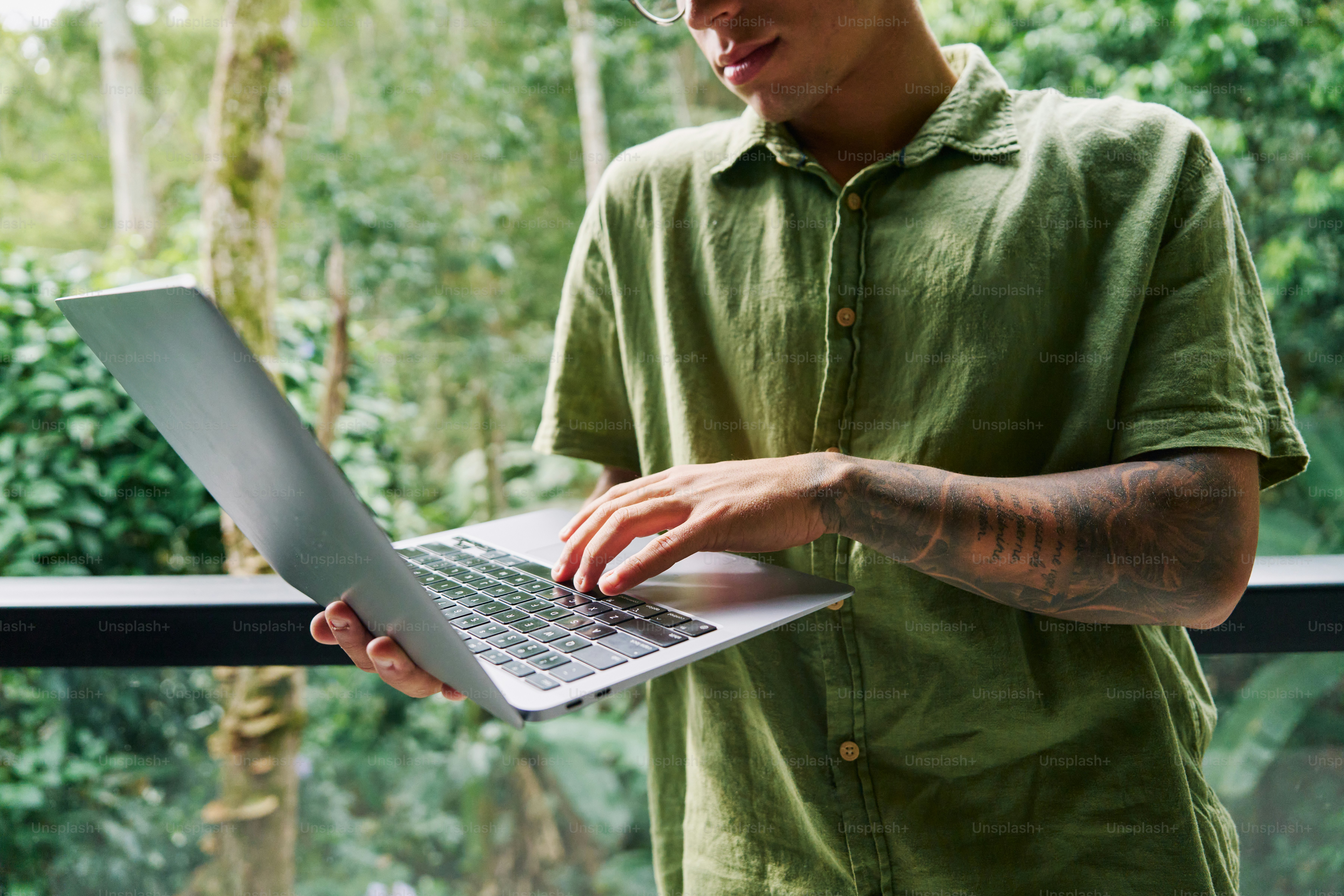 A man in a green shirt is using a laptop