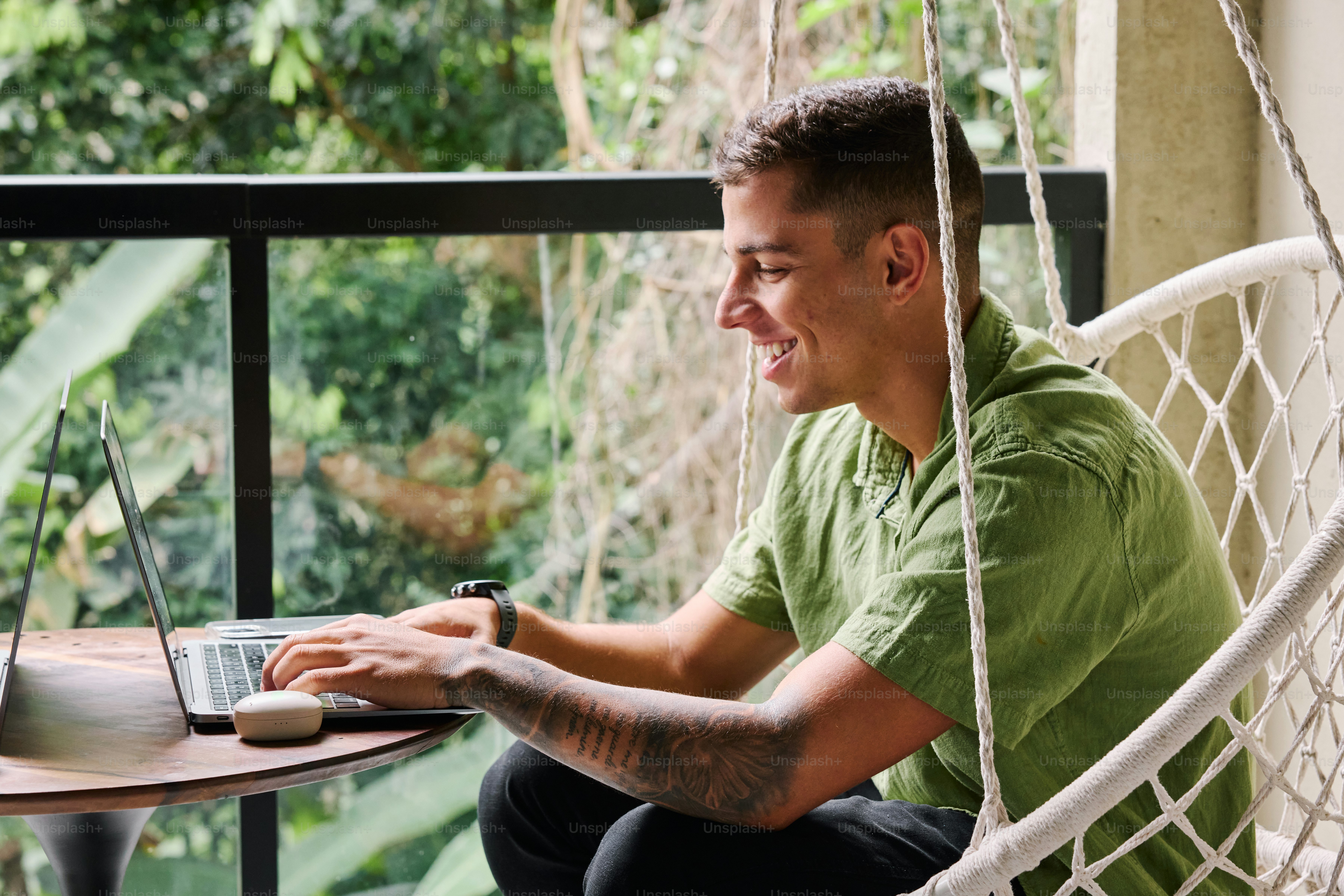 A man sitting in a hammock using a laptop