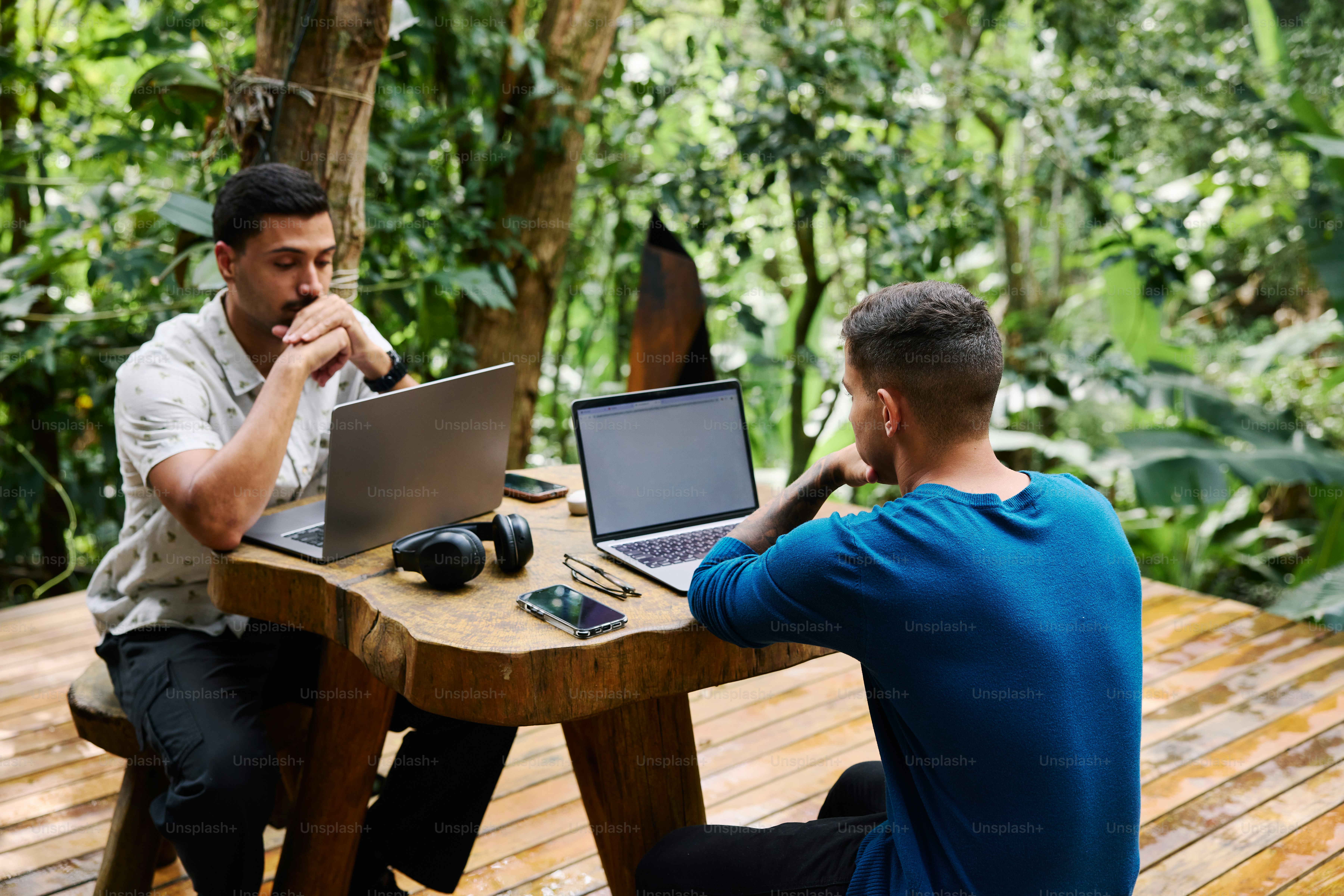 Two men sitting at a table with laptops