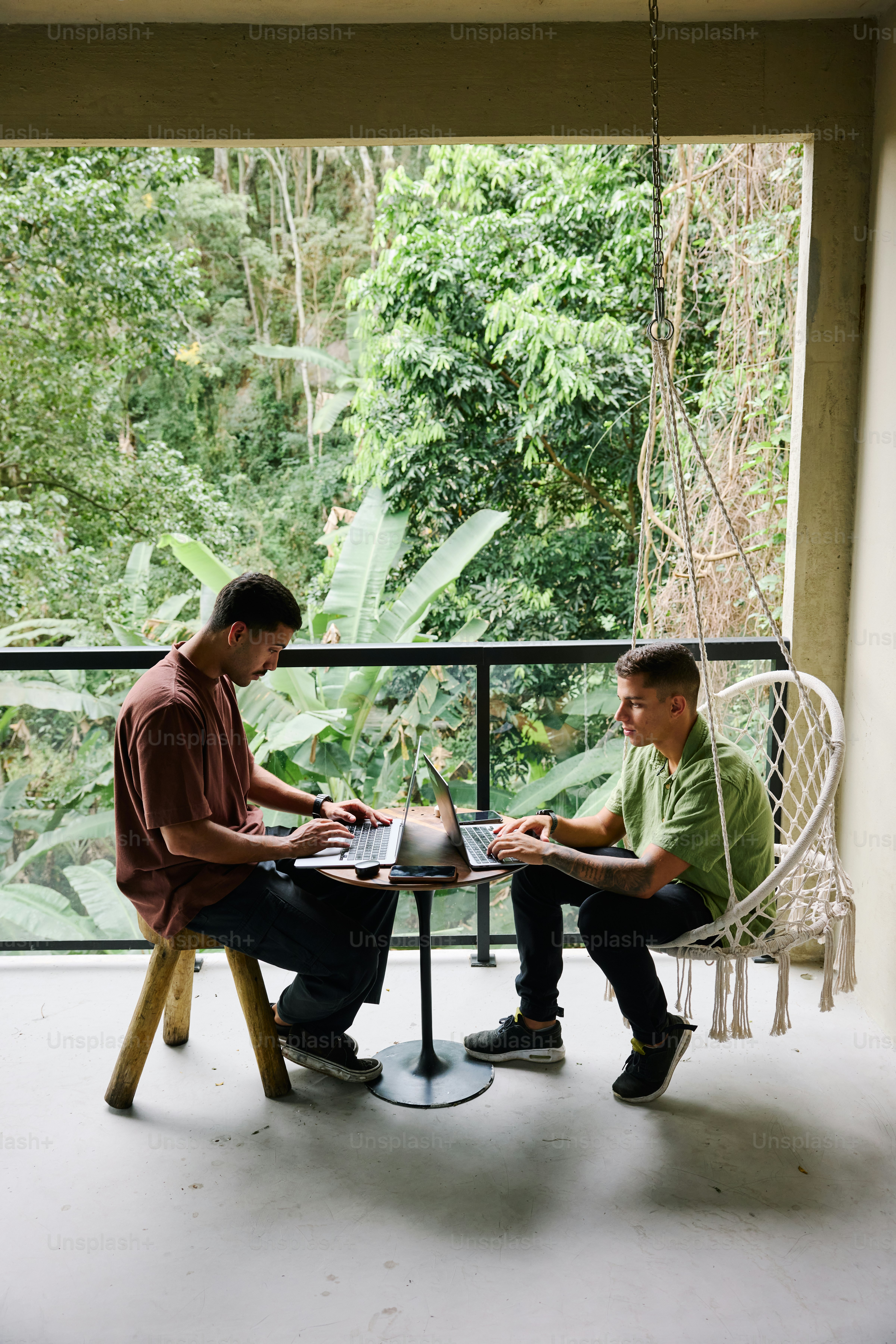 Two men sitting at a table on a porch