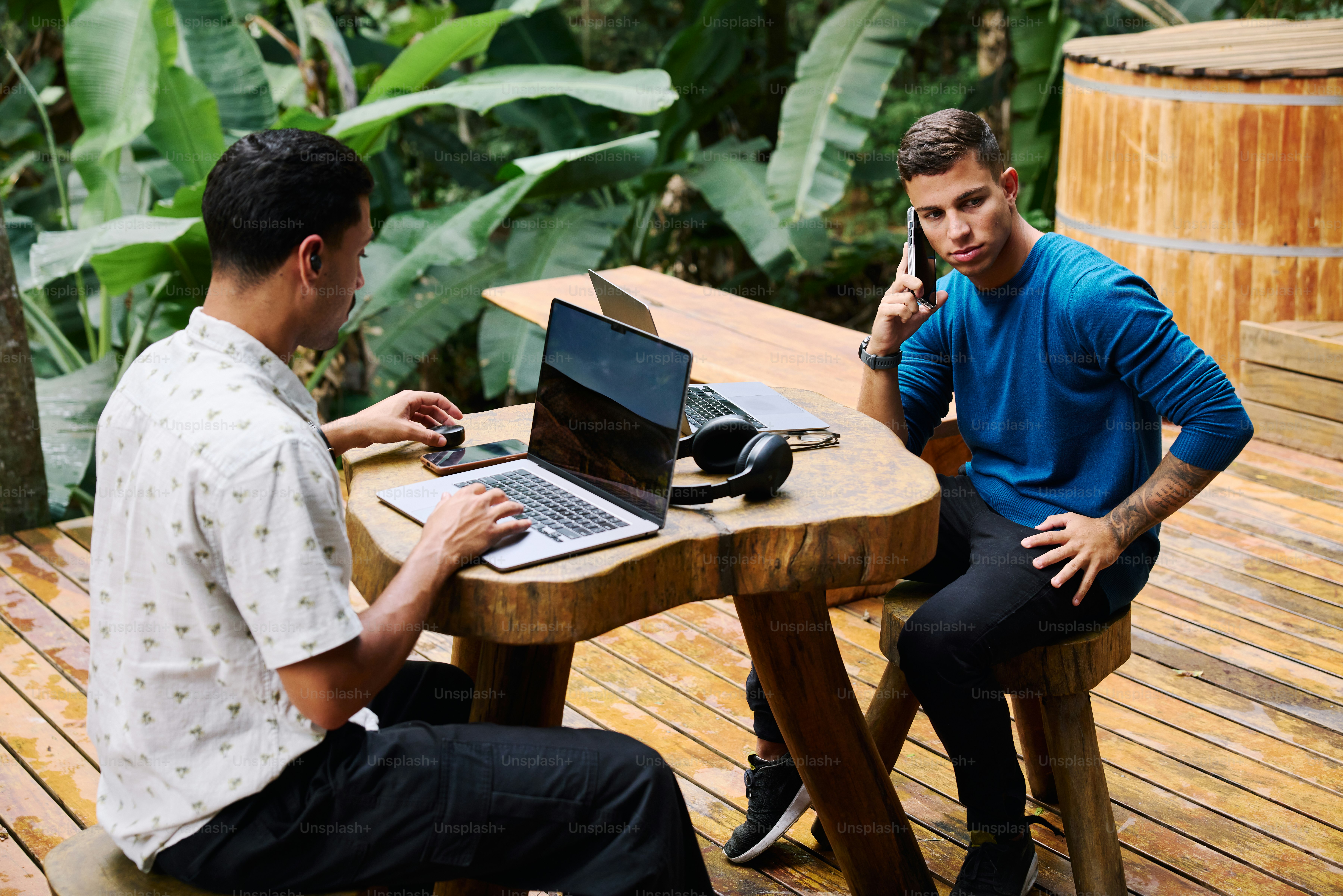 Um par de homens sentados em uma mesa com laptops