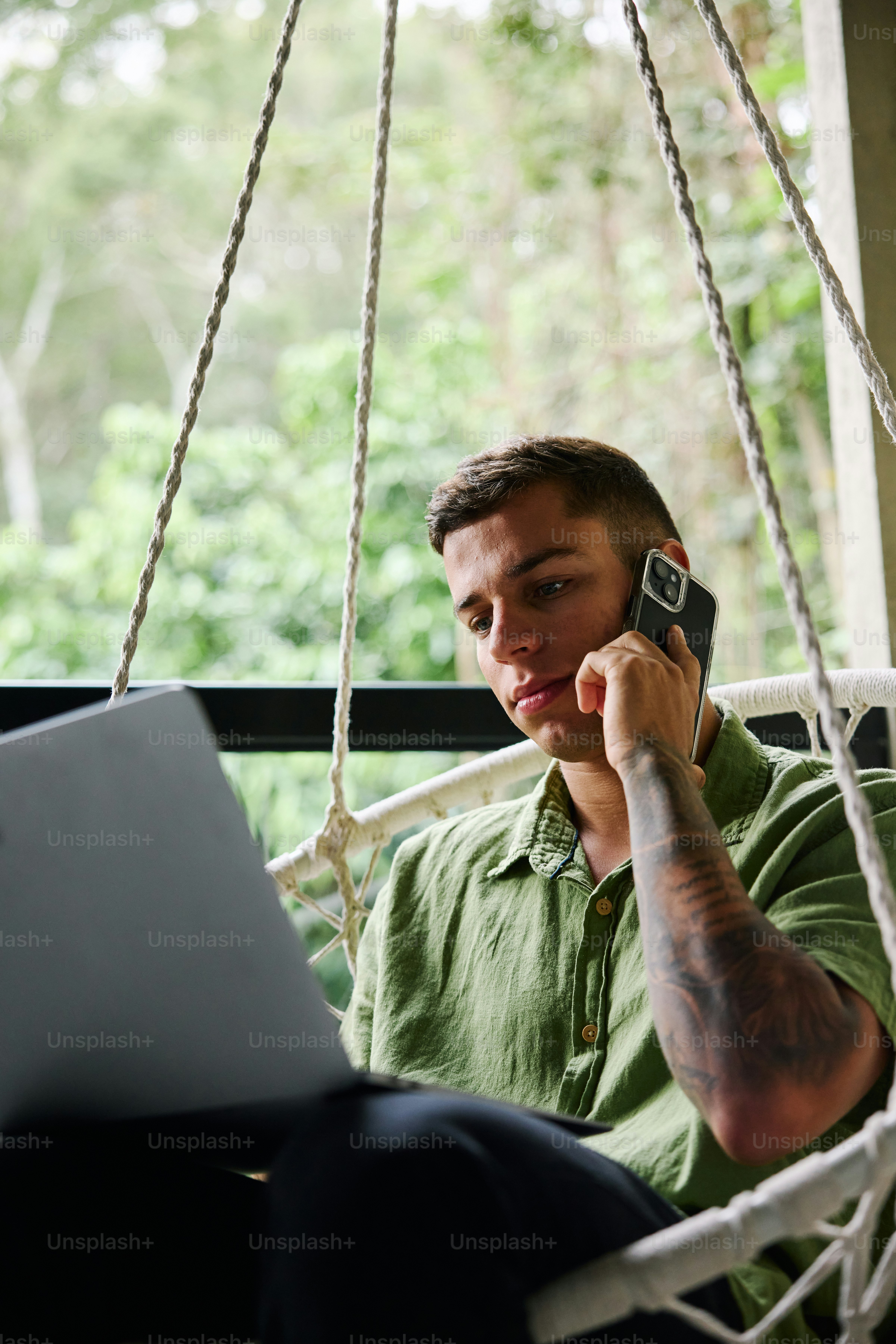 A man sitting in a hammock with a laptop on his lap