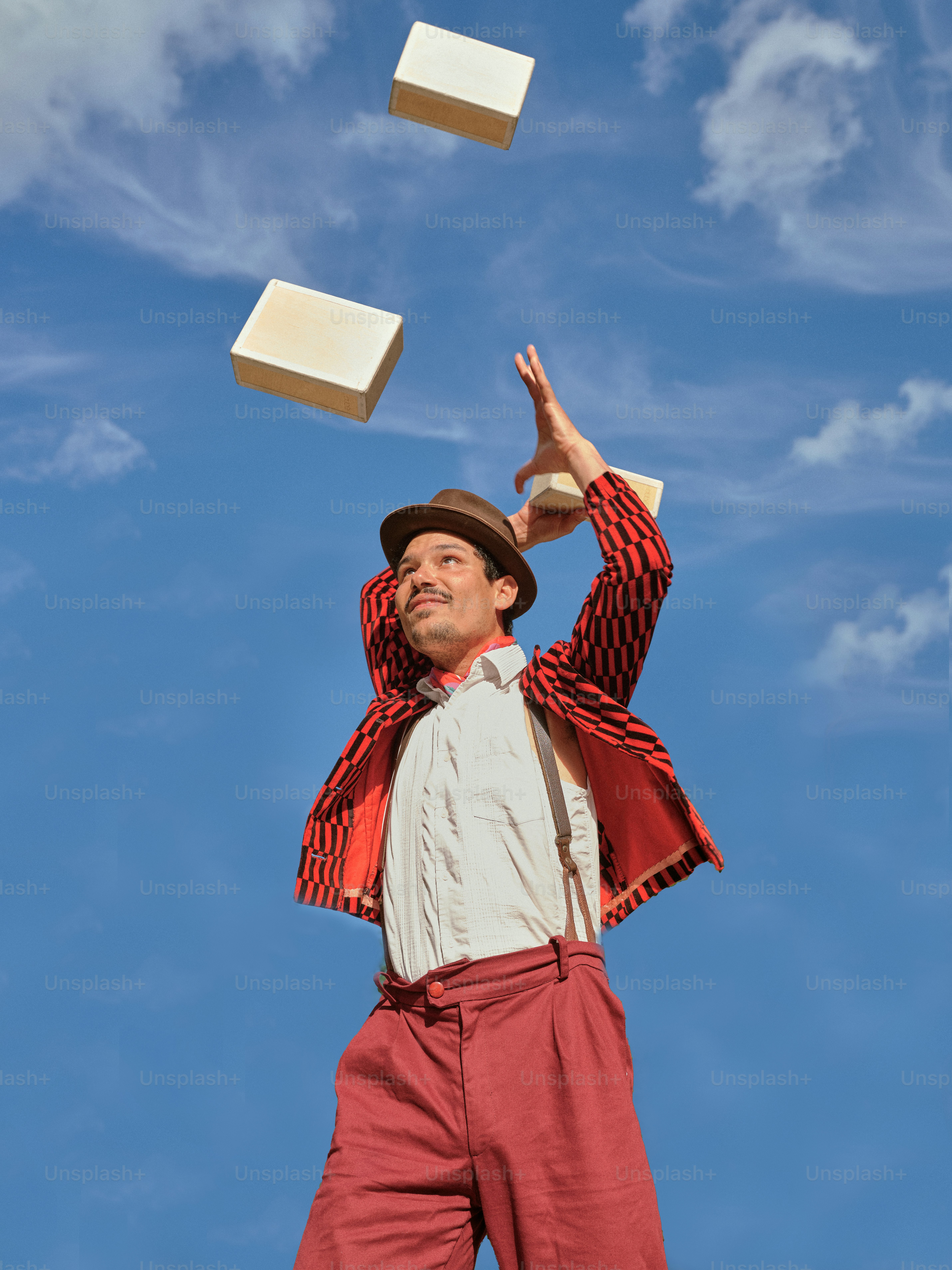 Ein Mann in roten Hosen und roter Jacke jongliert mit Würfeln in der Luft