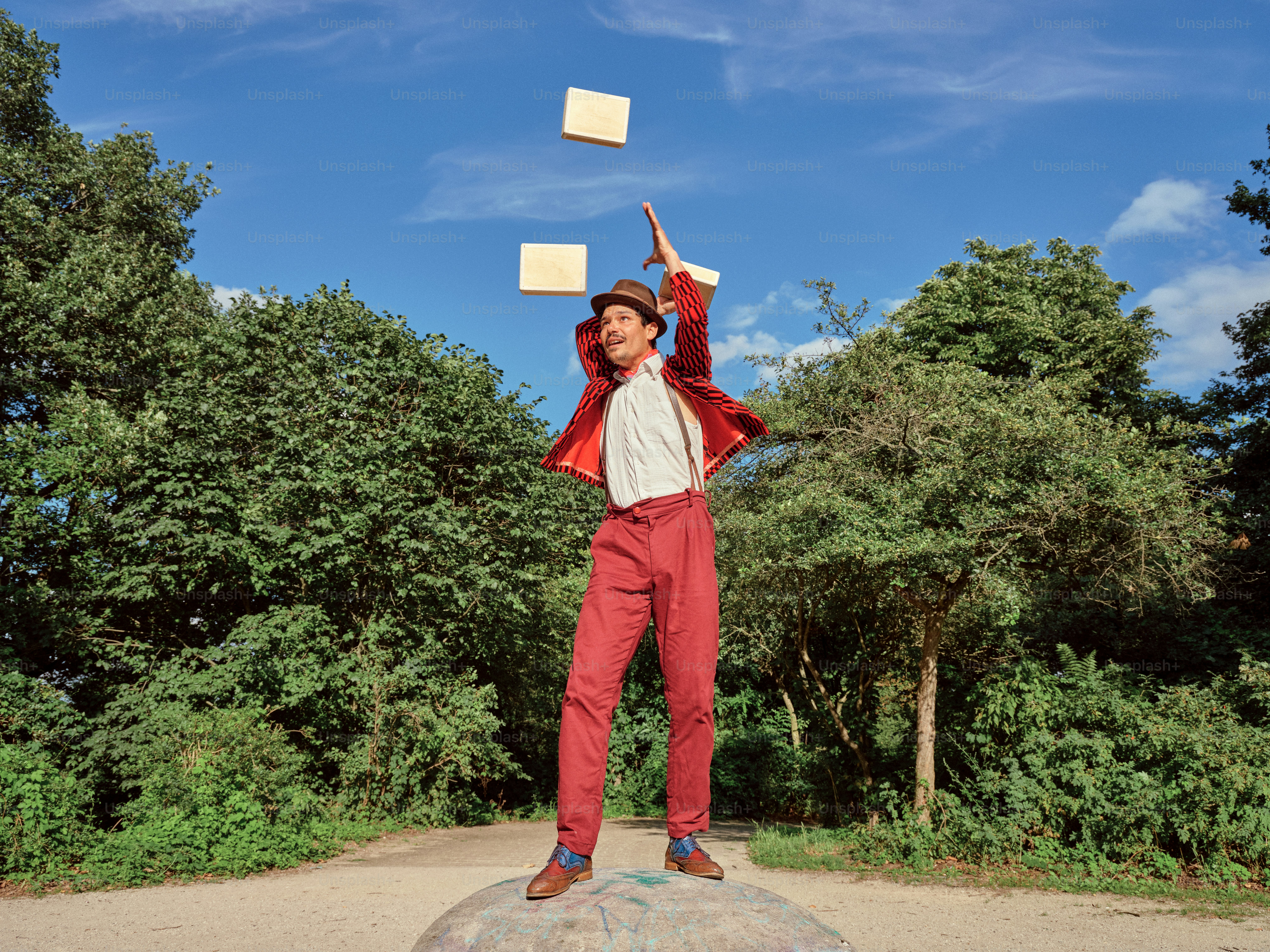 A man standing on top of a rock throwing papers in the air