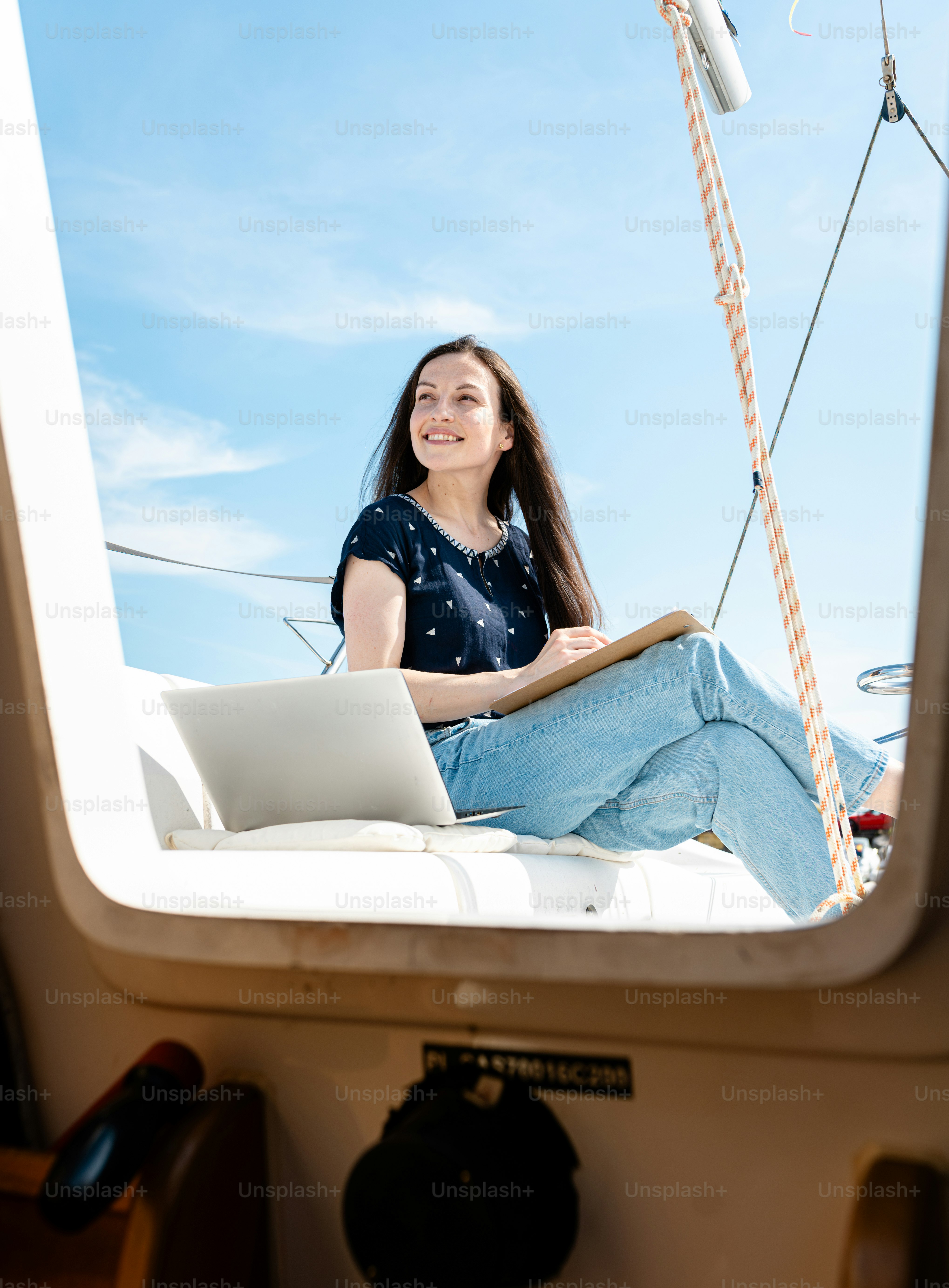 A woman sitting on a boat with a laptop