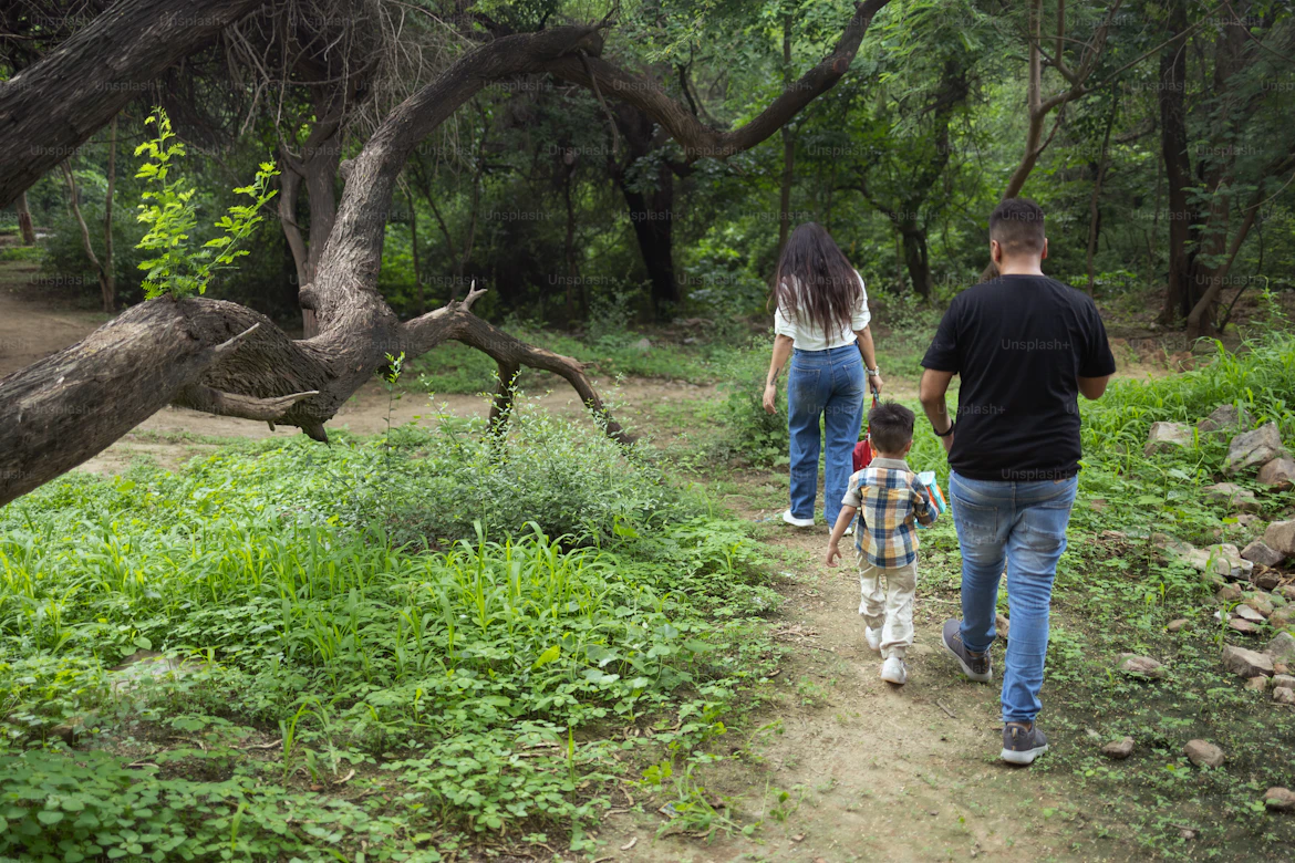 Parent and child walking hand in hand on a forest path.