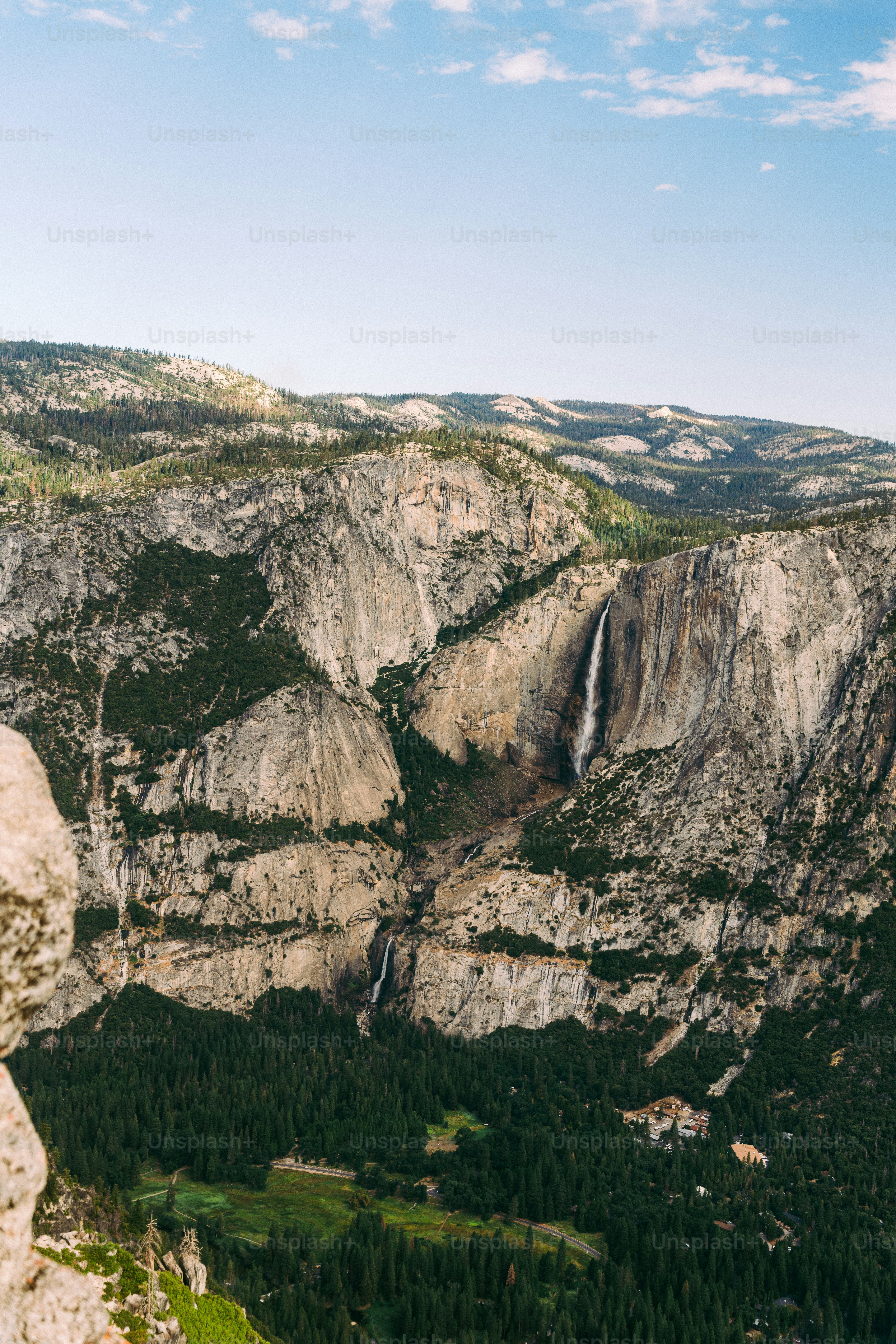 A man standing on top of a mountain next to a waterfall