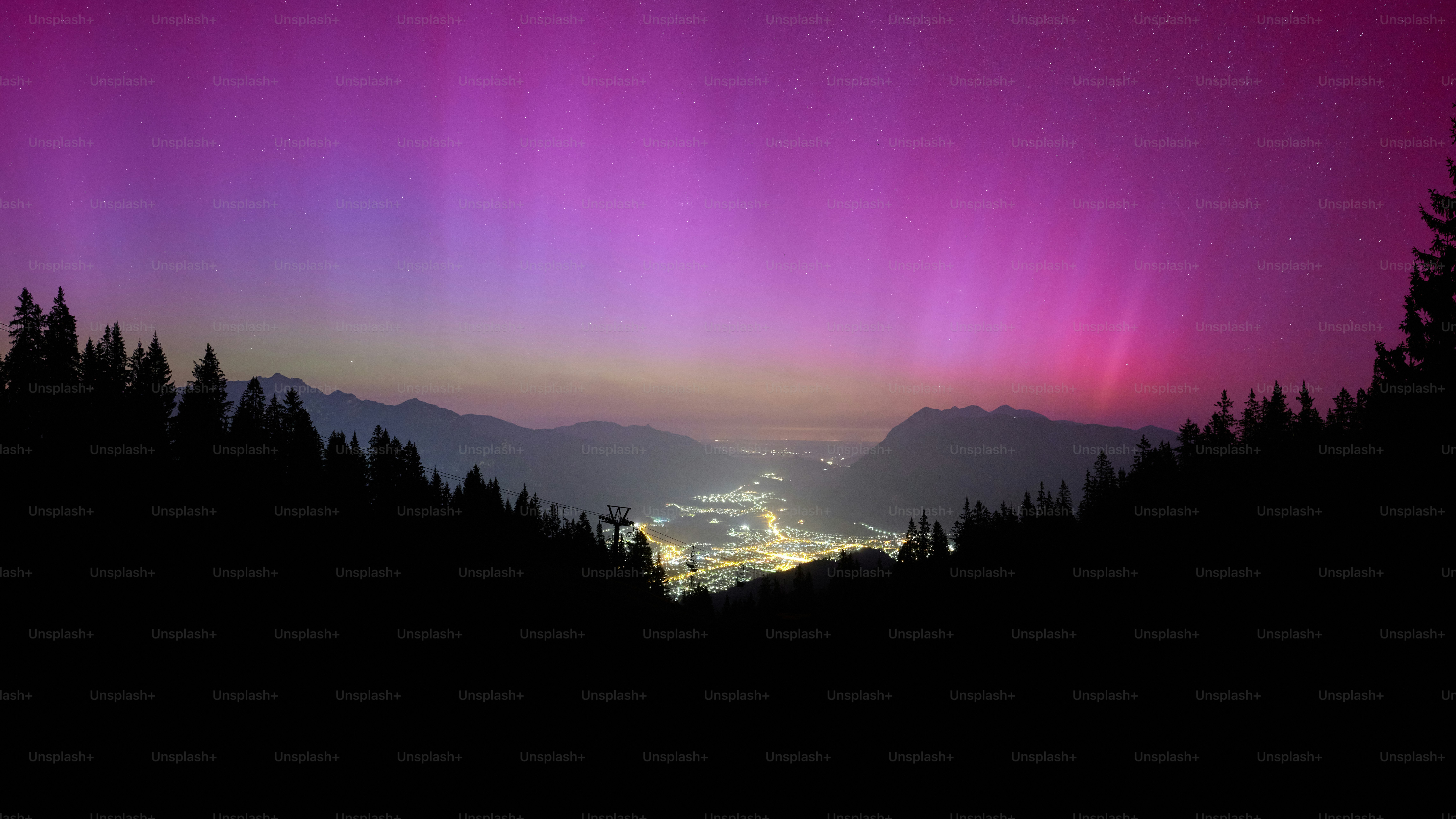 A purple and green aurora over a mountain range