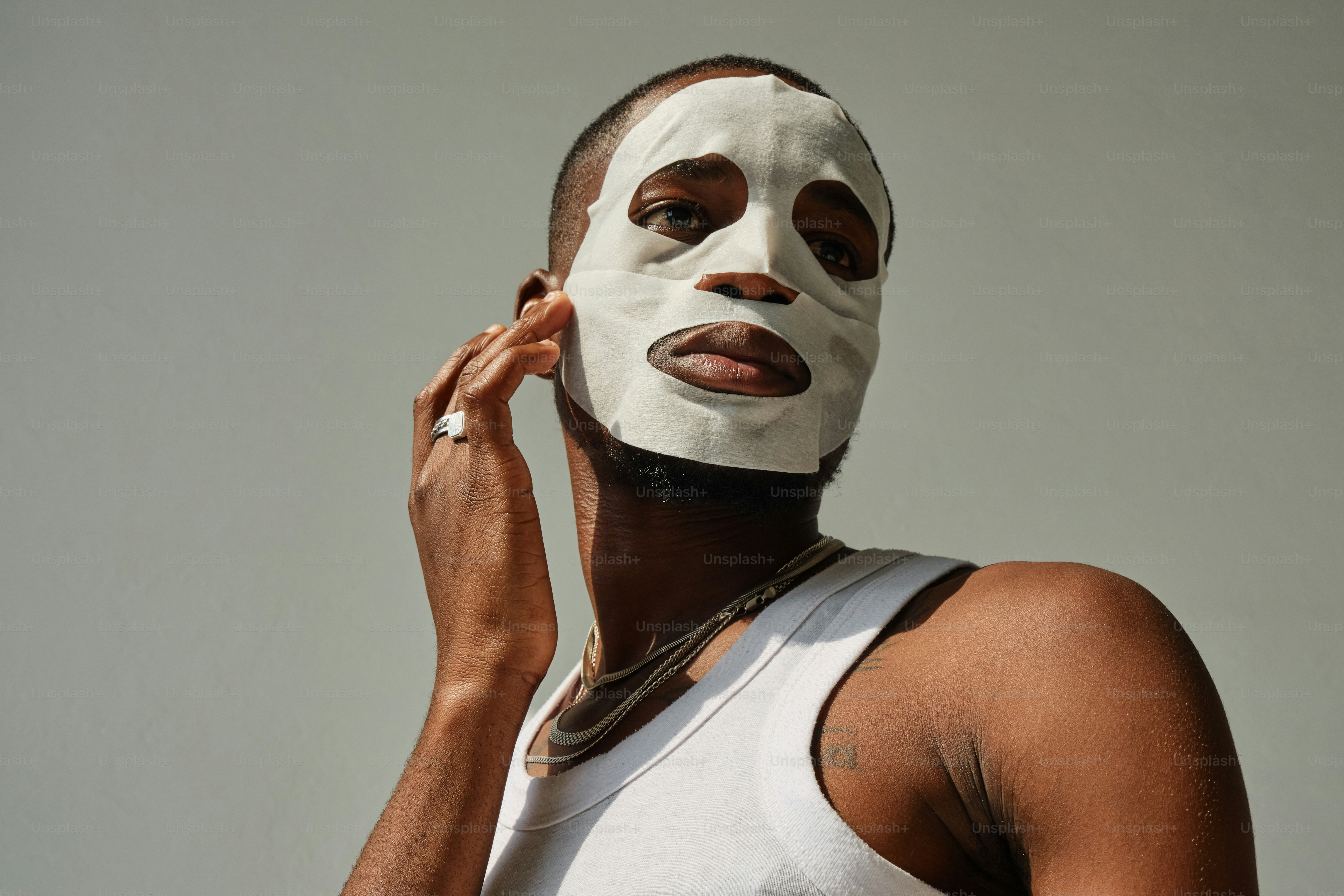 A man wearing a white mask talking on a cell phone