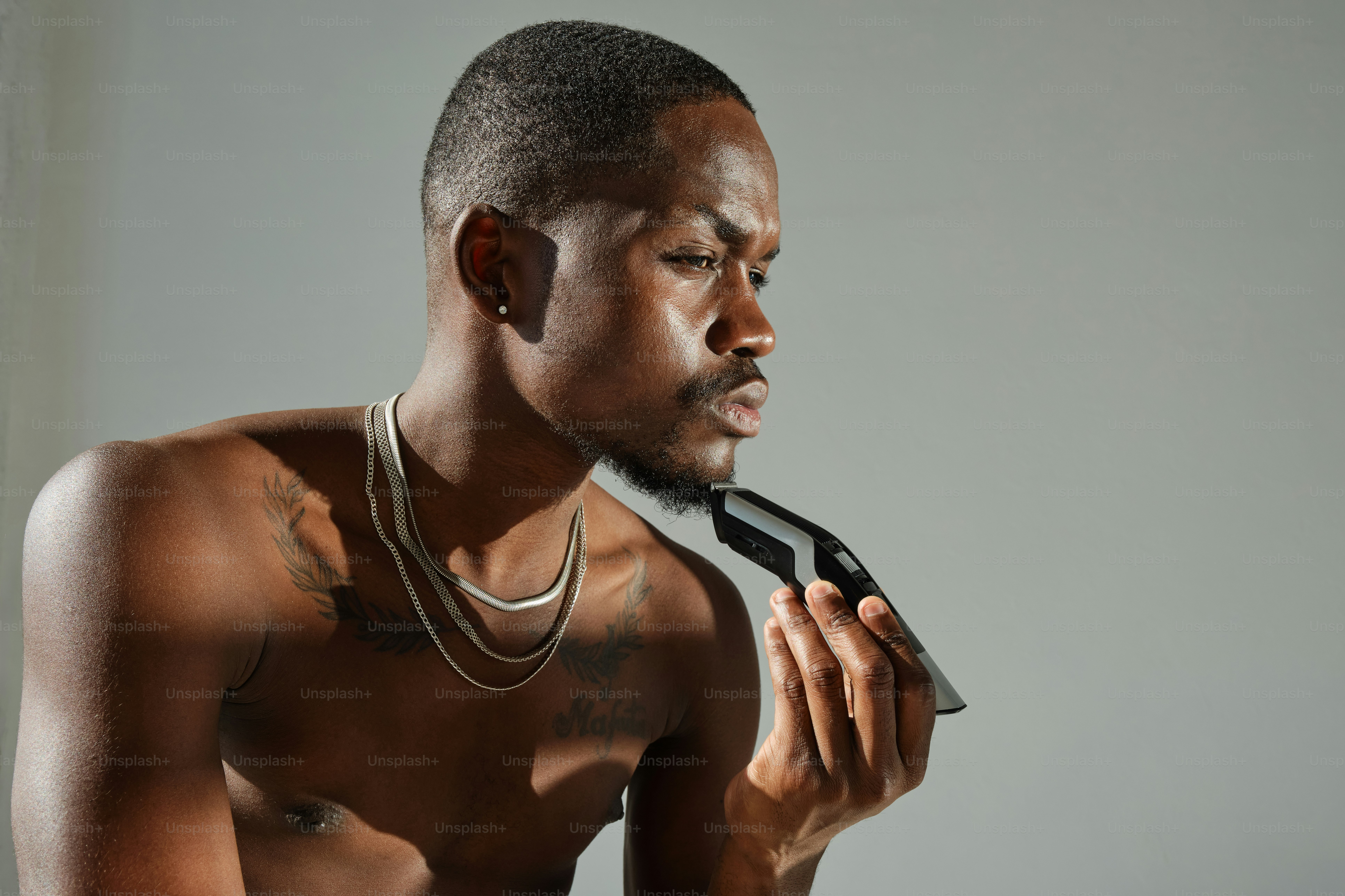 A shirtless man holding a hair dryer in his hand