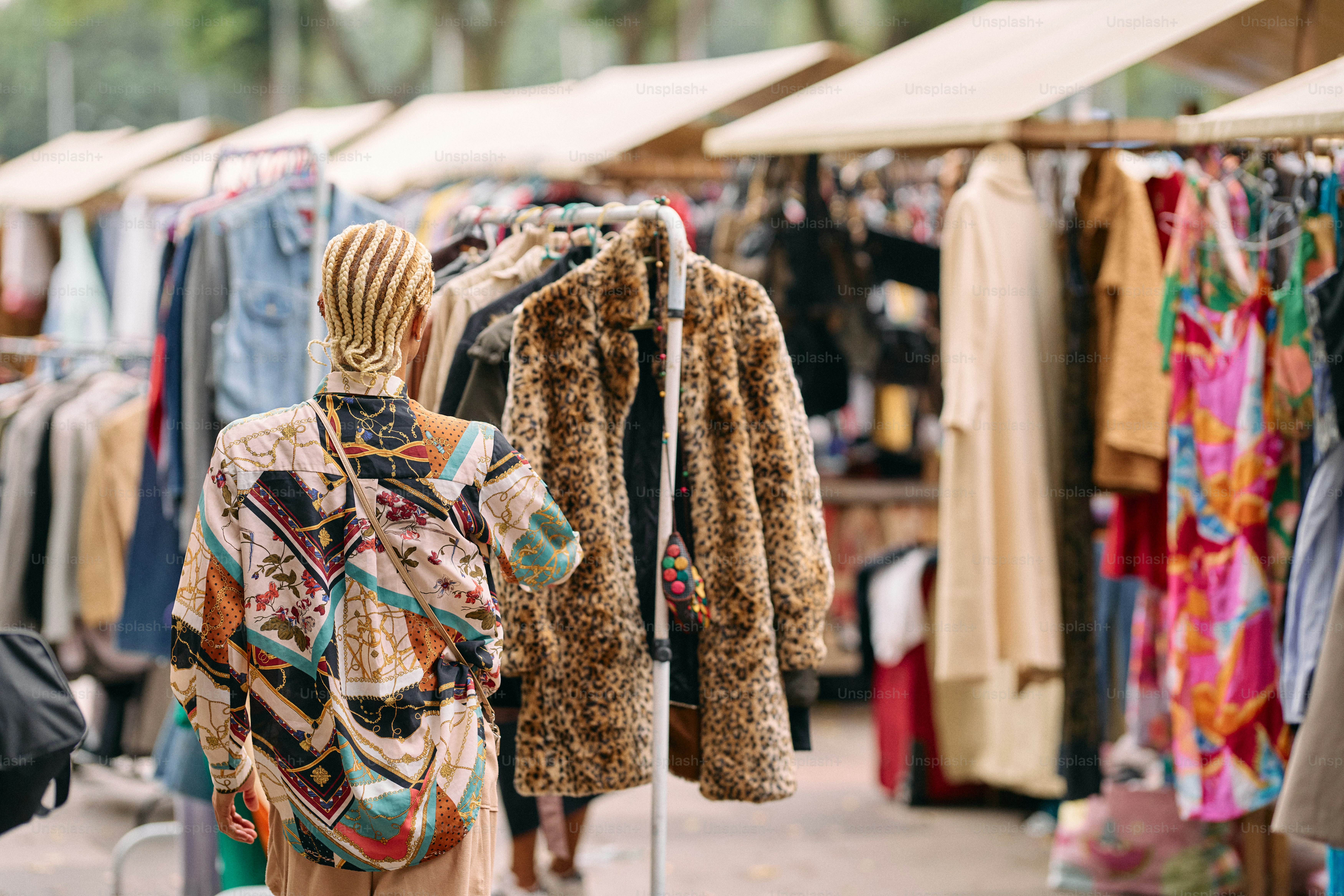 A woman walking down a street next to a row of clothes