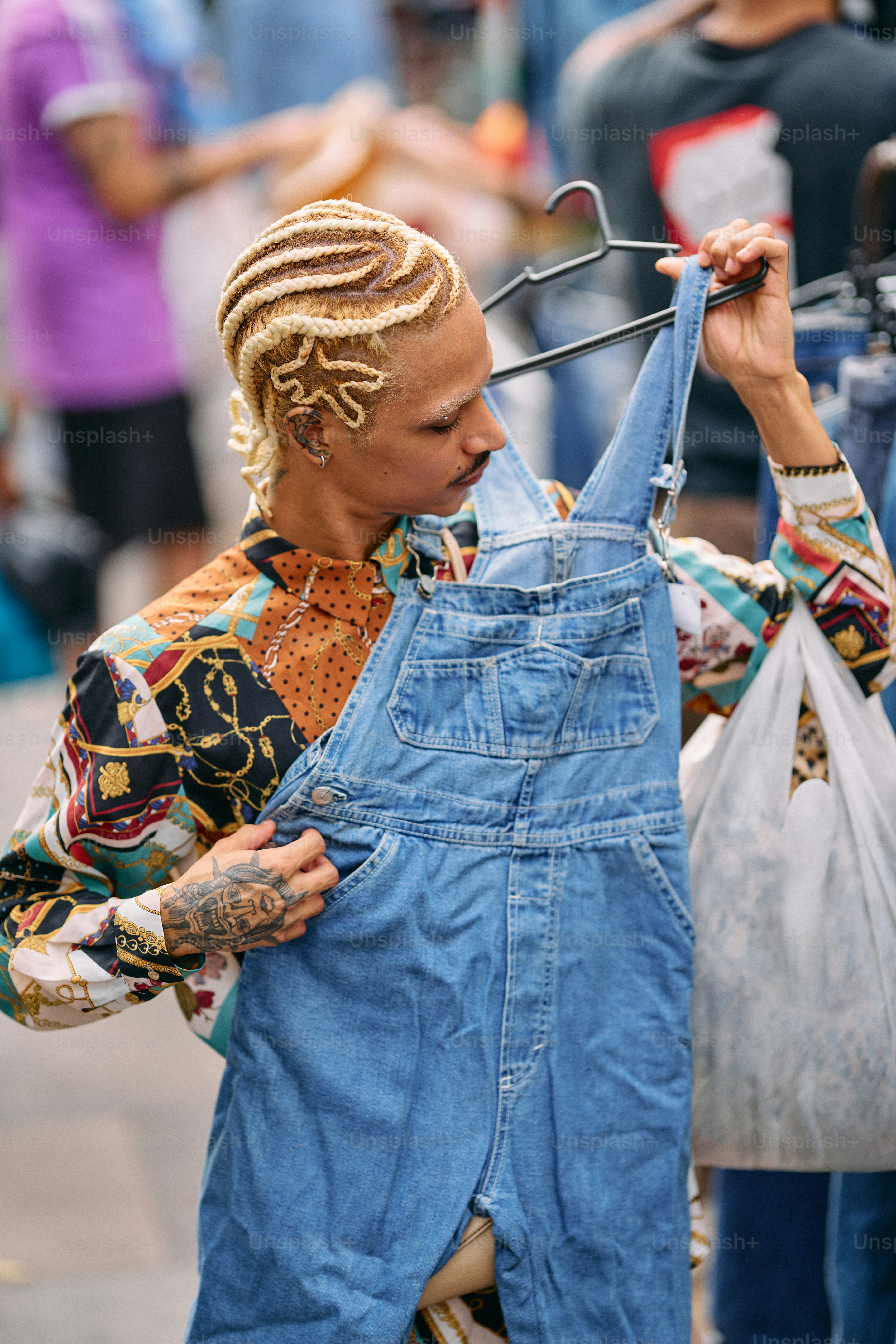 A woman with dreadlocks is holding a pair of overalls