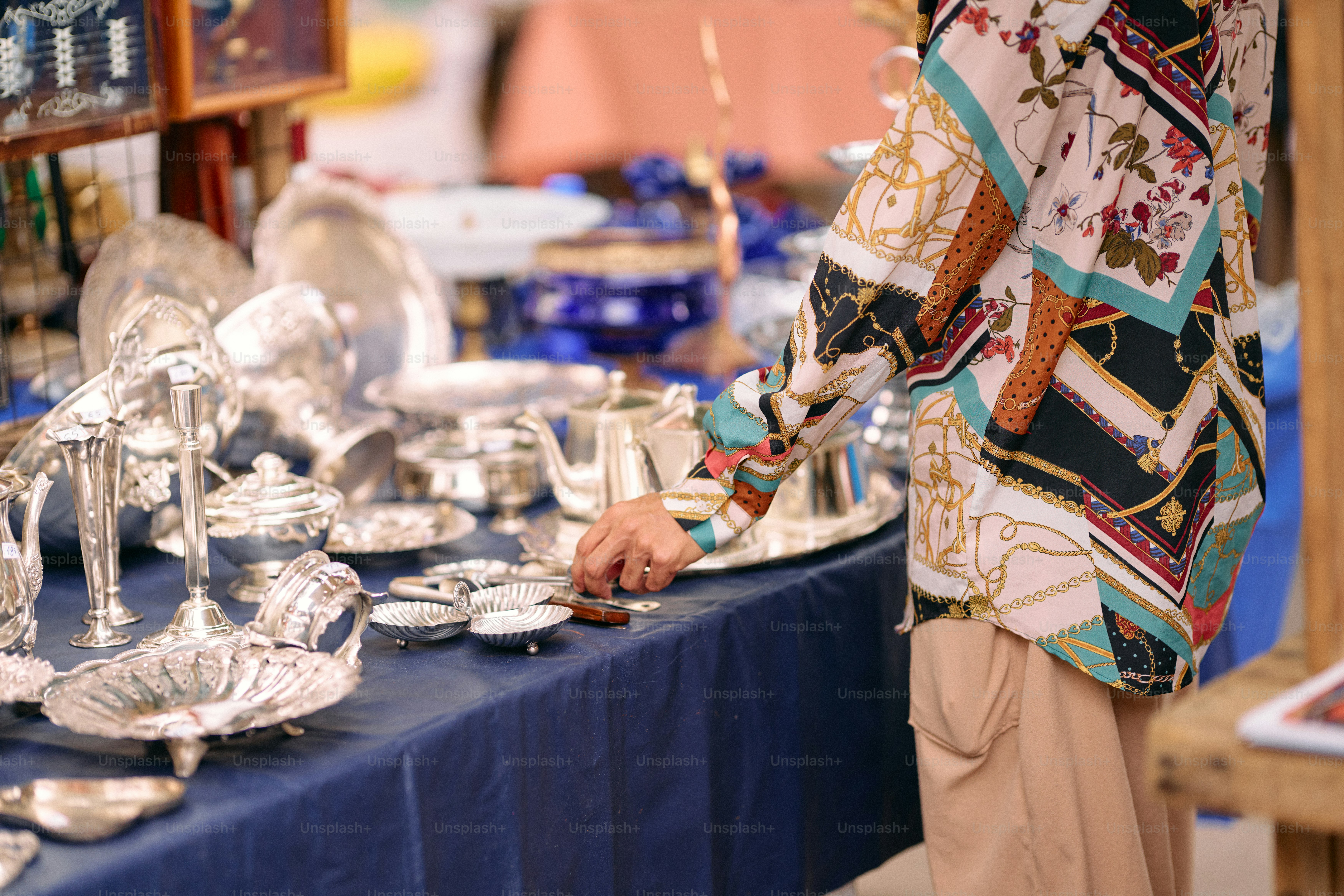 A woman standing next to a table filled with silverware