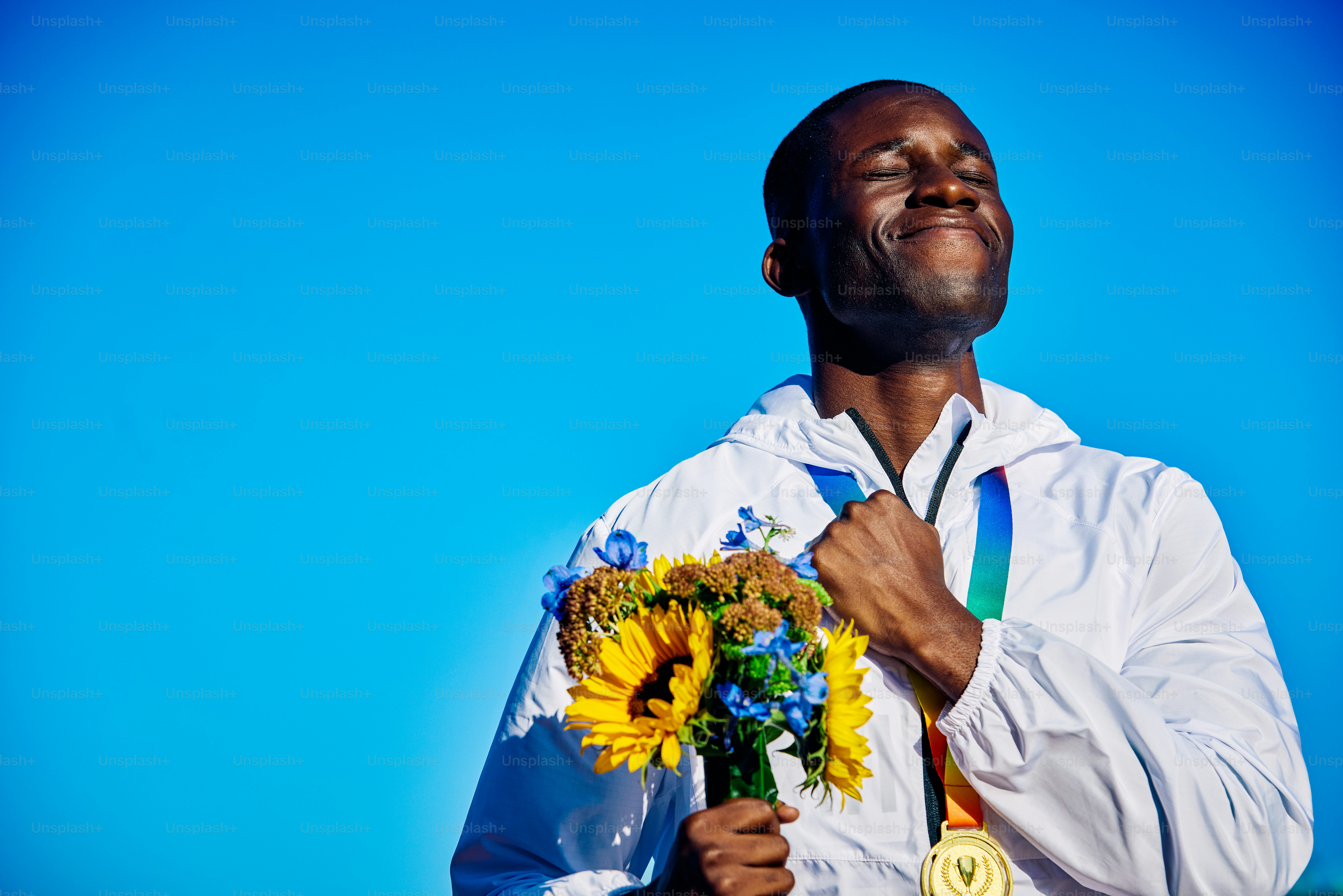 Content International athlete clutching gold medal with a bouquet of sunflowers. Serene victory portrait with blue sky. Fulfillment and gratitude concept