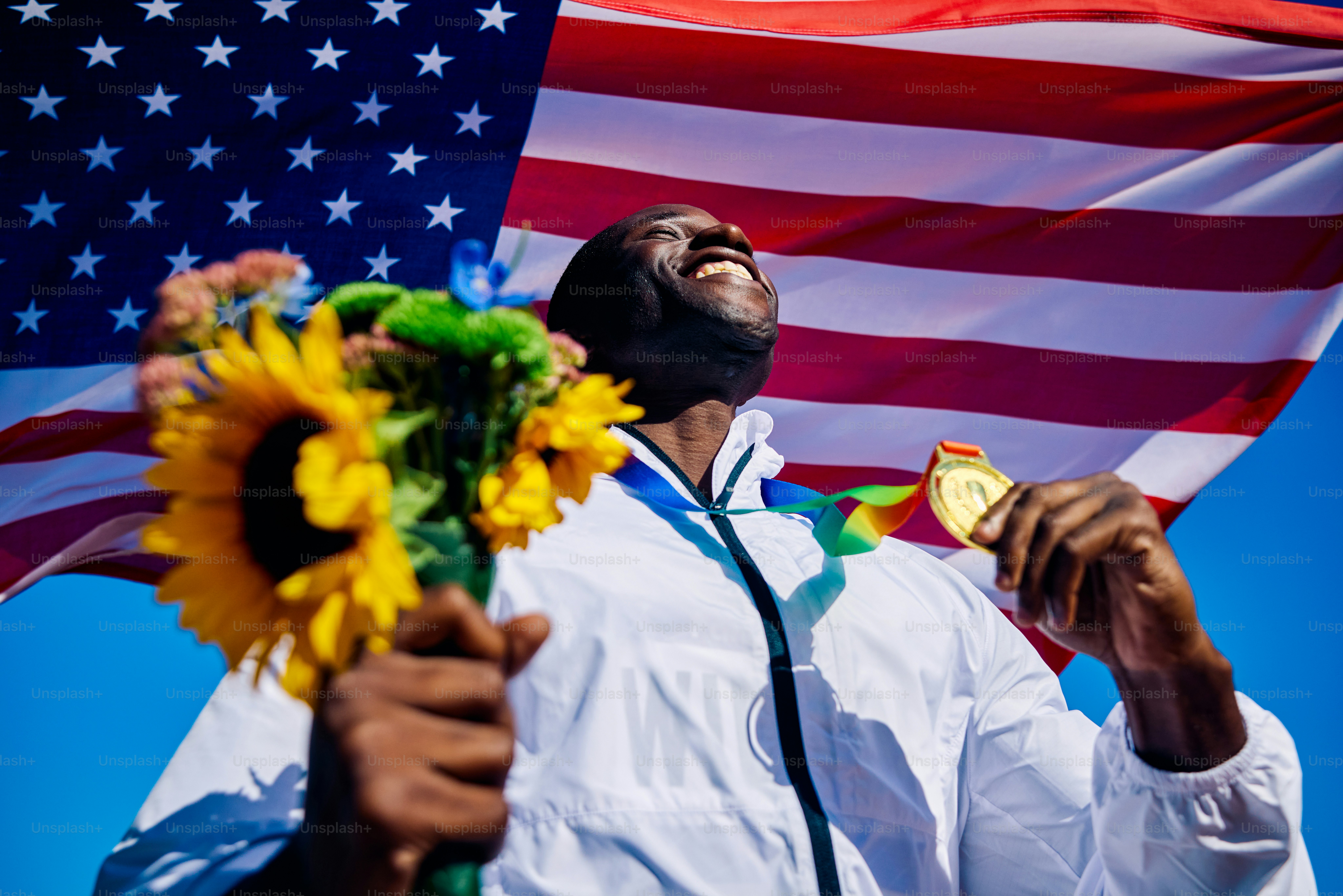 Exuberant athlete standing on the podium with an American flag in the background. International sports event concept outdoor portrait.