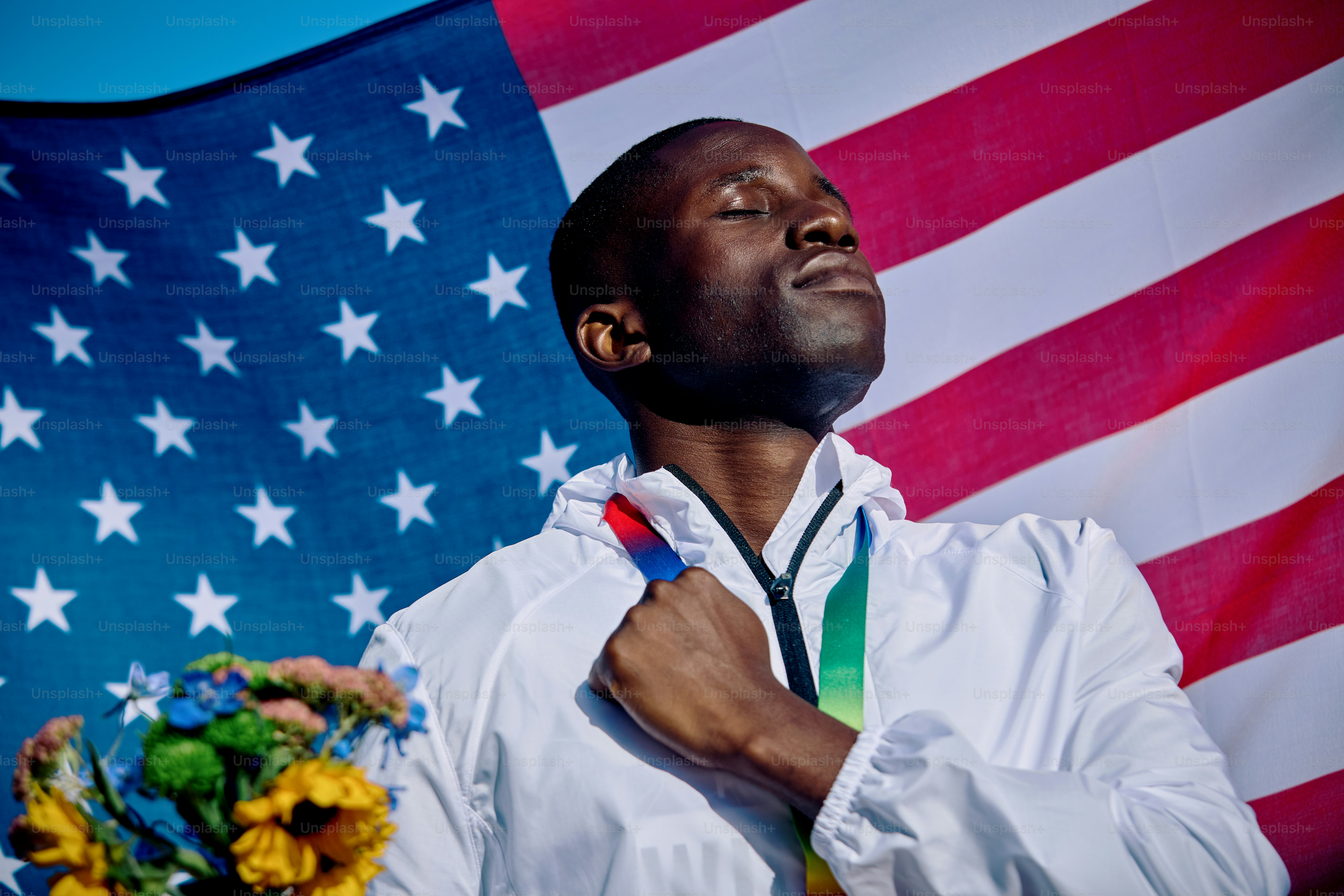Exuberant athlete standing on the podium with an American flag in the background. International sports event concept outdoor portrait.