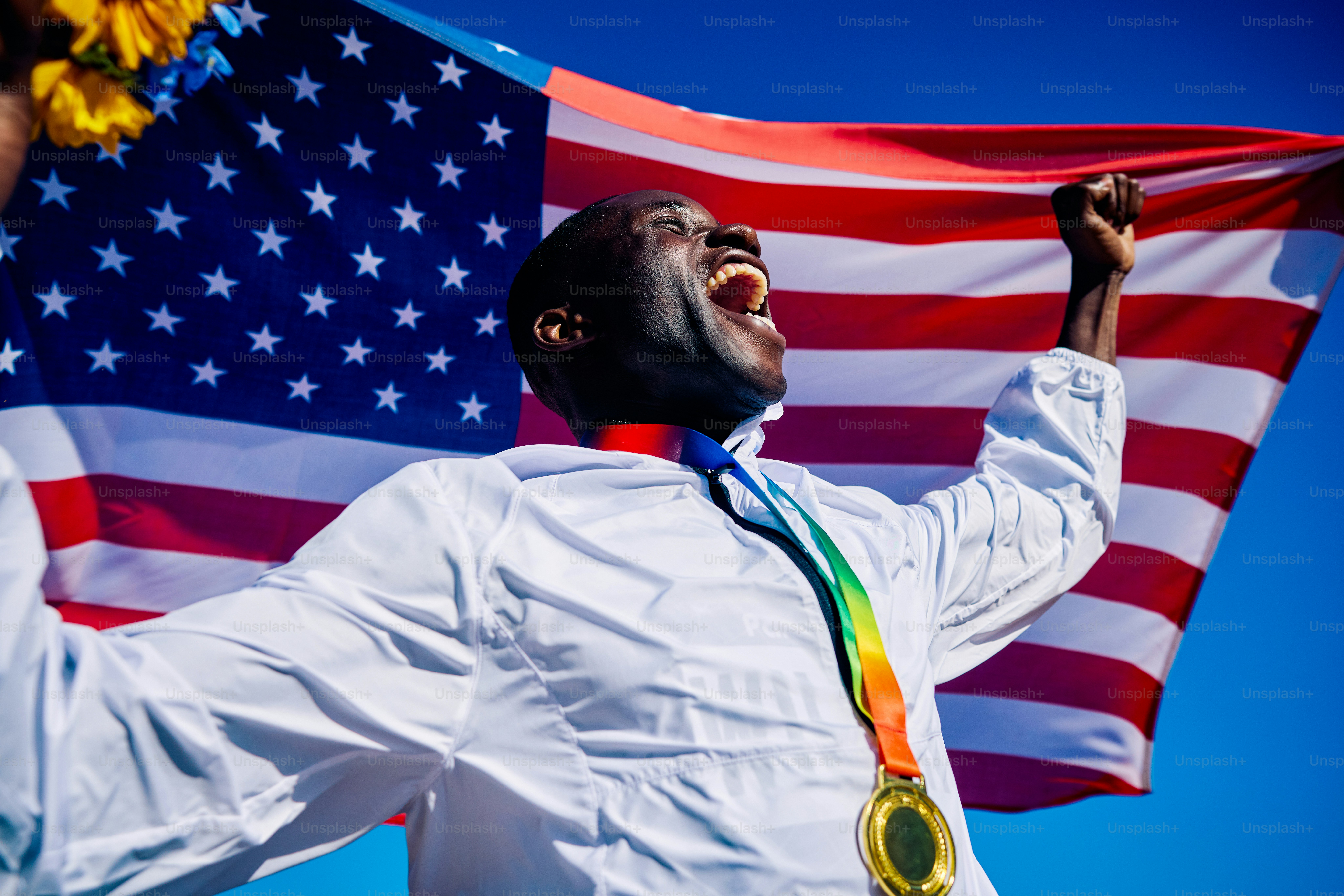 Exuberant athlete standing on the podium with an American flag in the background. International sports event concept outdoor portrait.