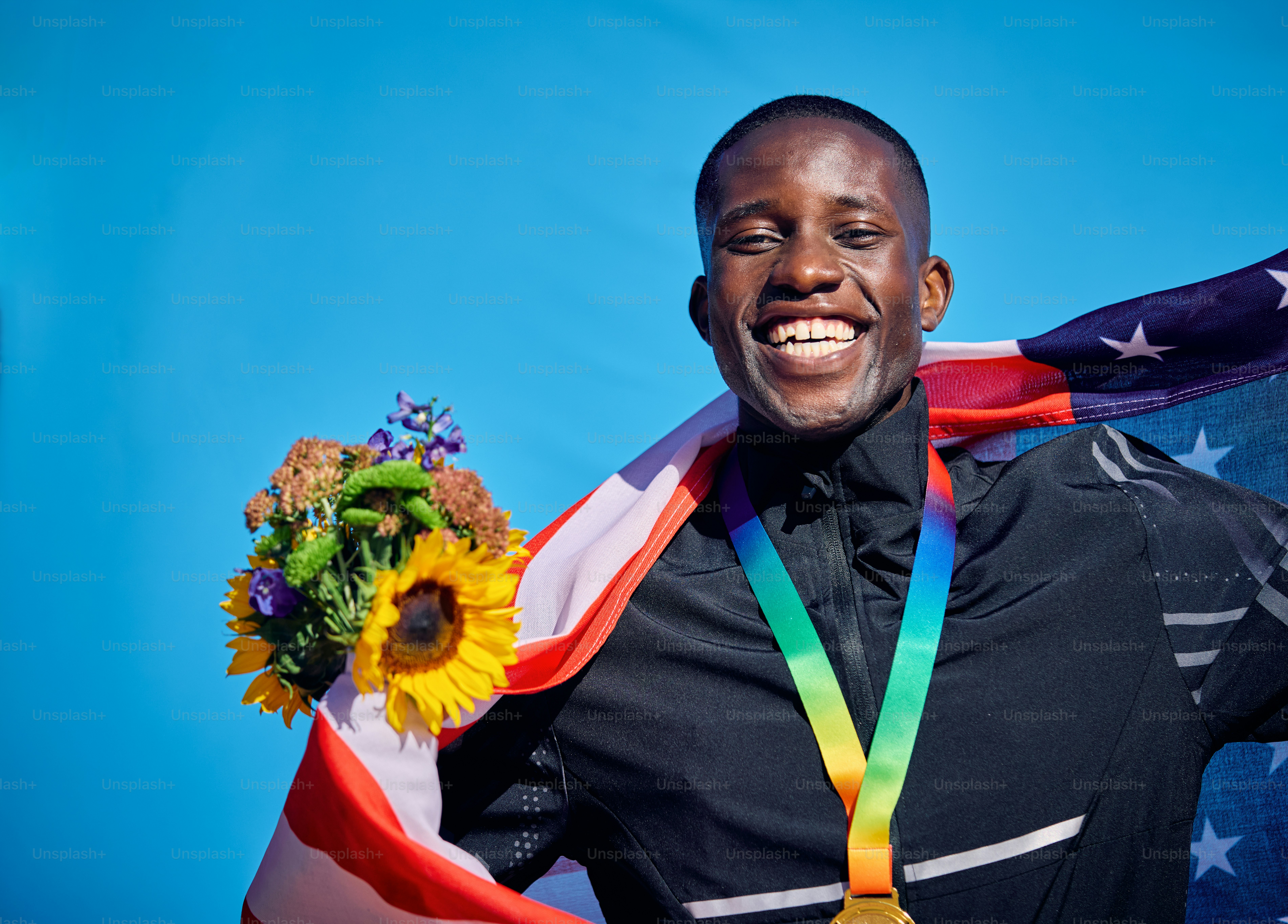 Stolzer Athlet in der Flagge der USA. Feier im Freien Porträt mit blauem Himmel Hintergrund. Sportliches Sieg- und Glückskonzept