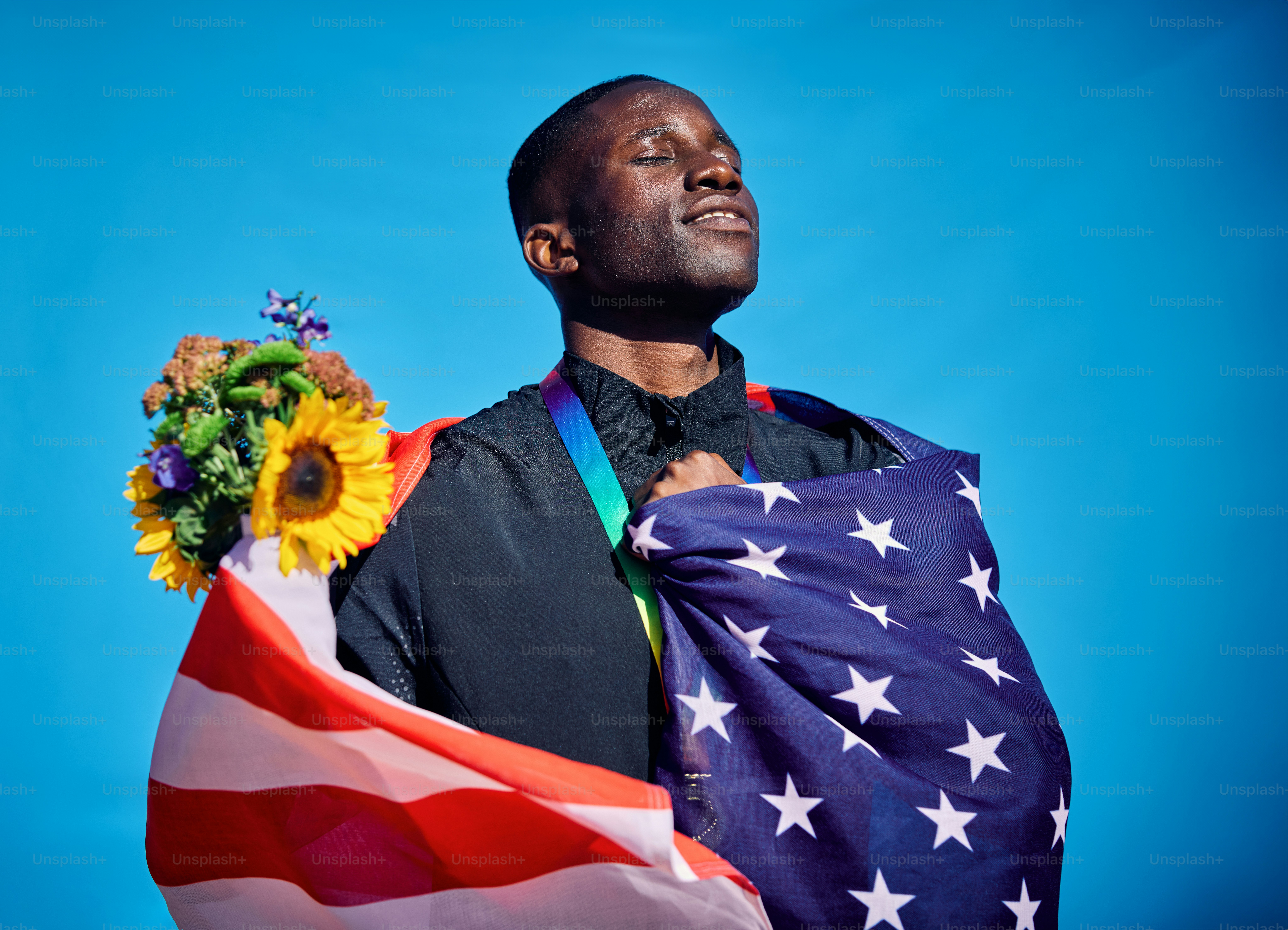 Stolzer Athlet in der Flagge der USA. Feier im Freien Porträt mit blauem Himmel Hintergrund. Sportliches Sieg- und Glückskonzept.