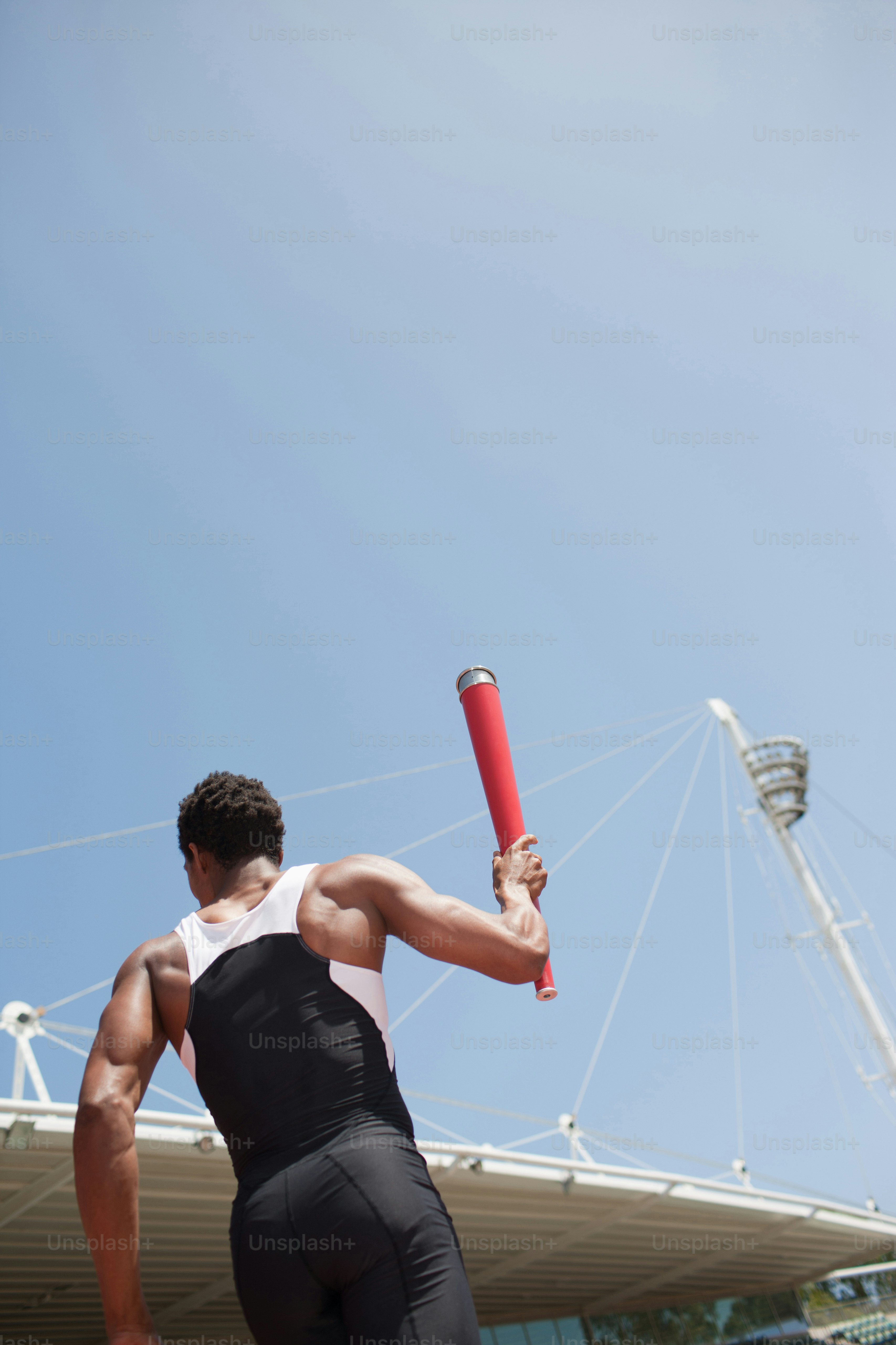 Un hombre sosteniendo un bate de béisbol frente a un estadio