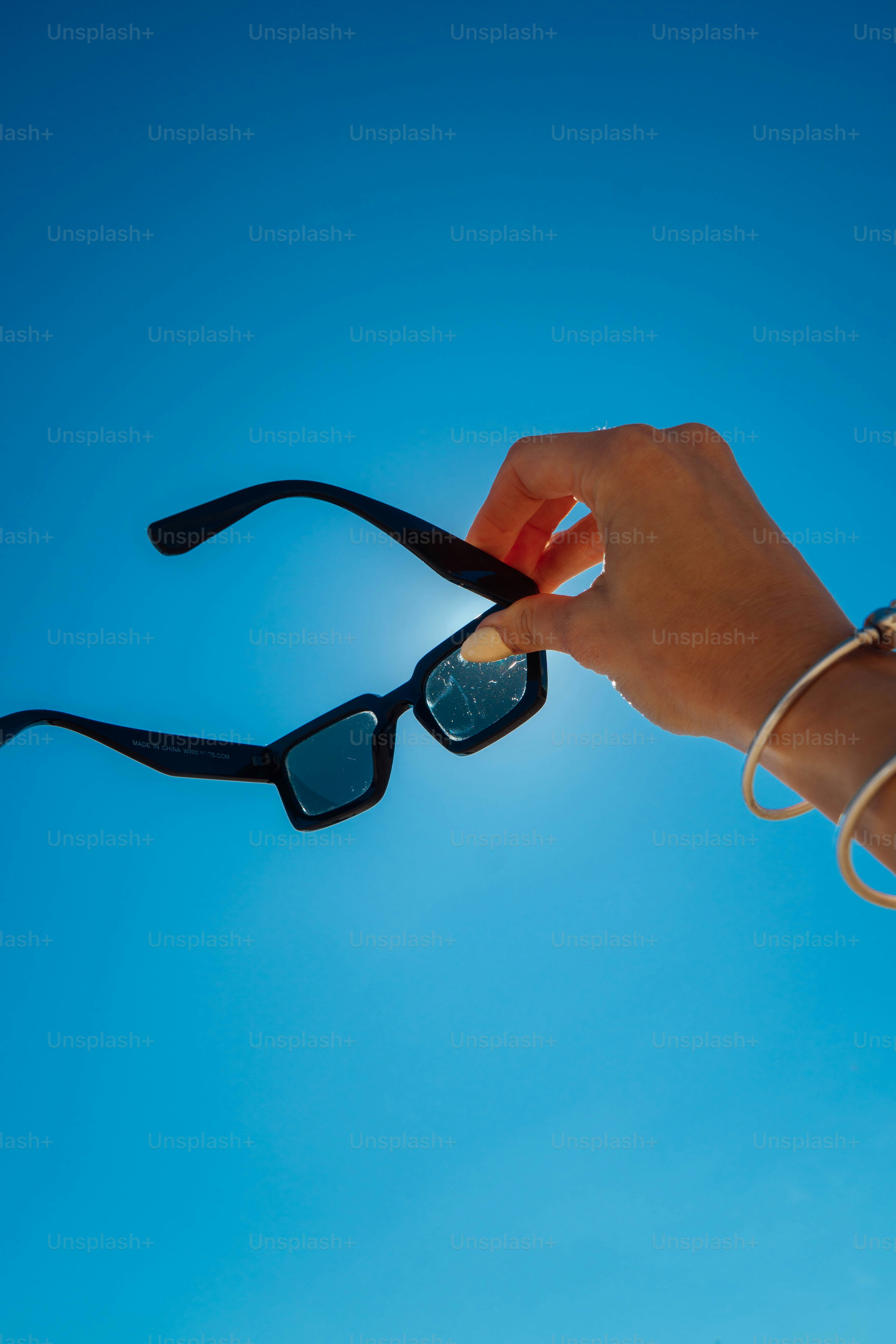A person holding onto a pair of sunglasses