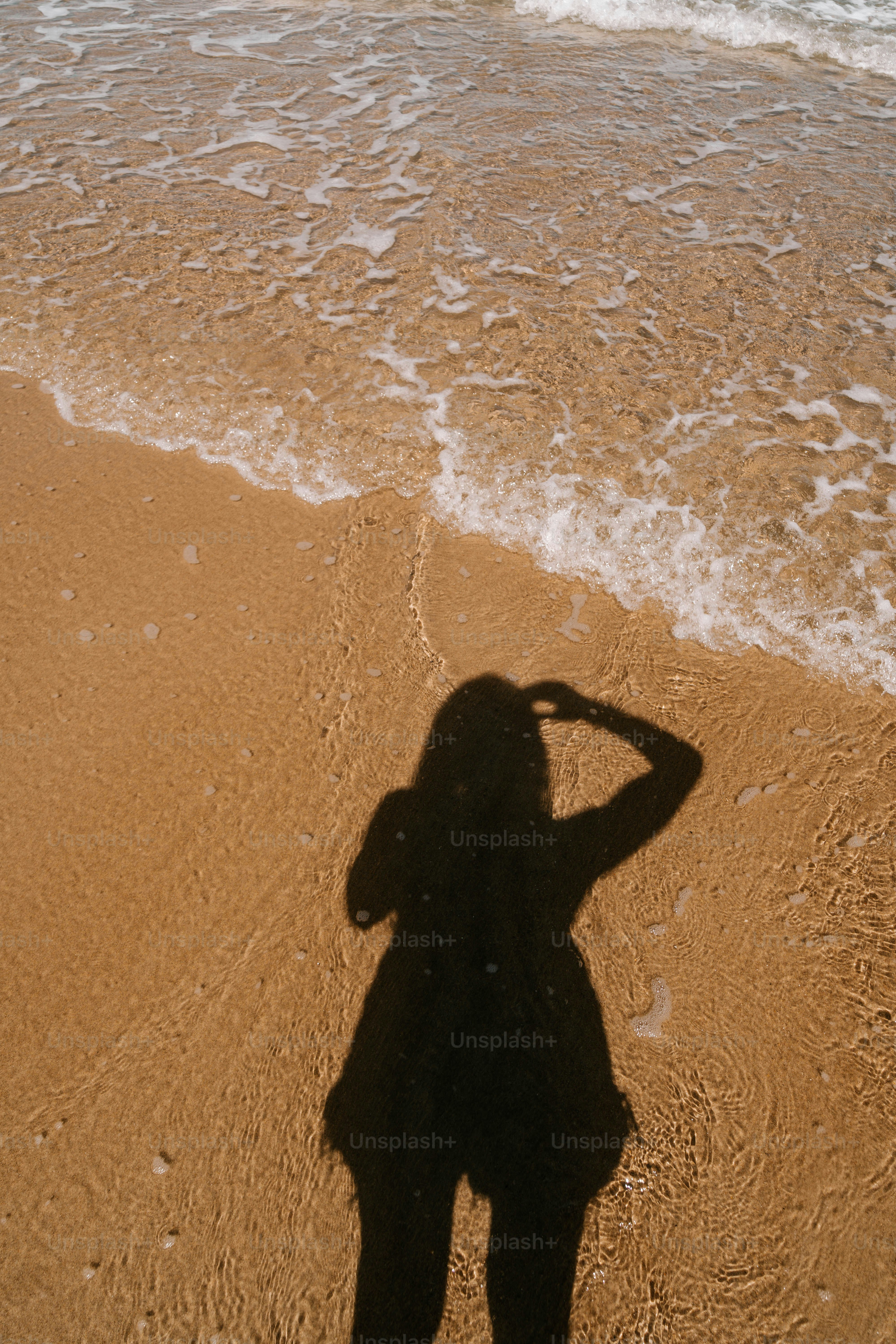 A shadow of a person standing on a beach
