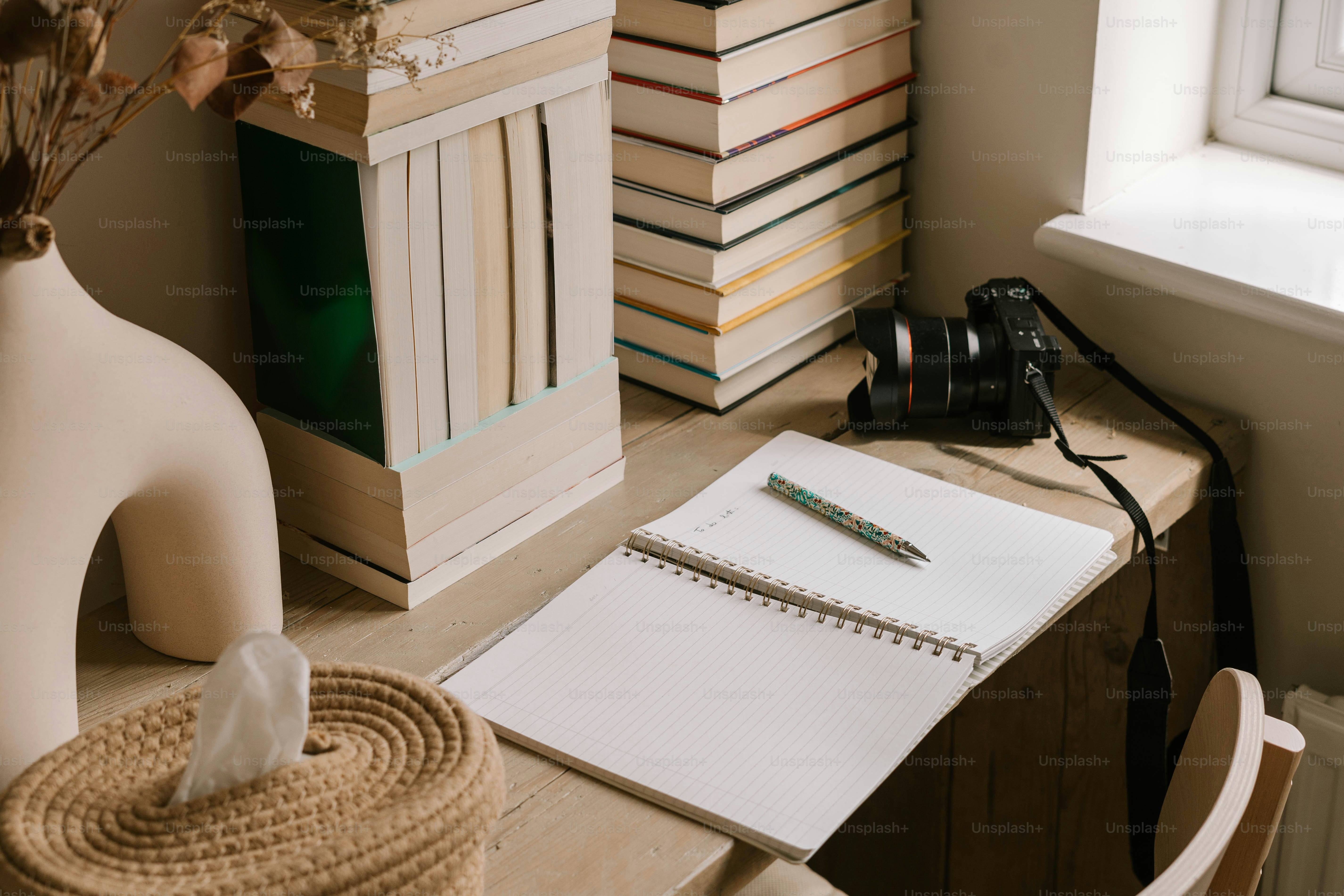 A stack of books and a vase of flowers on a desk