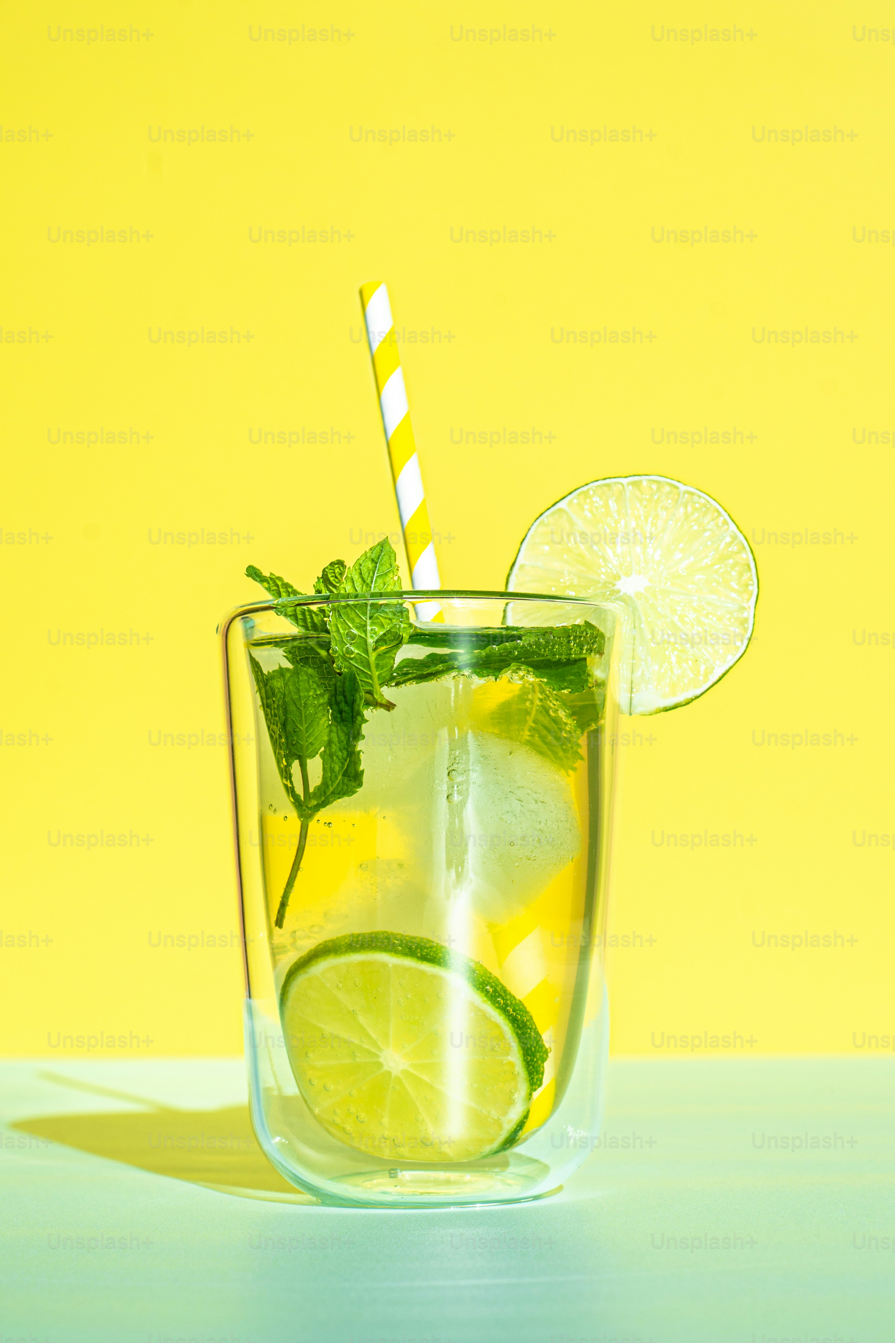 A glass of lemonade with a straw and lime