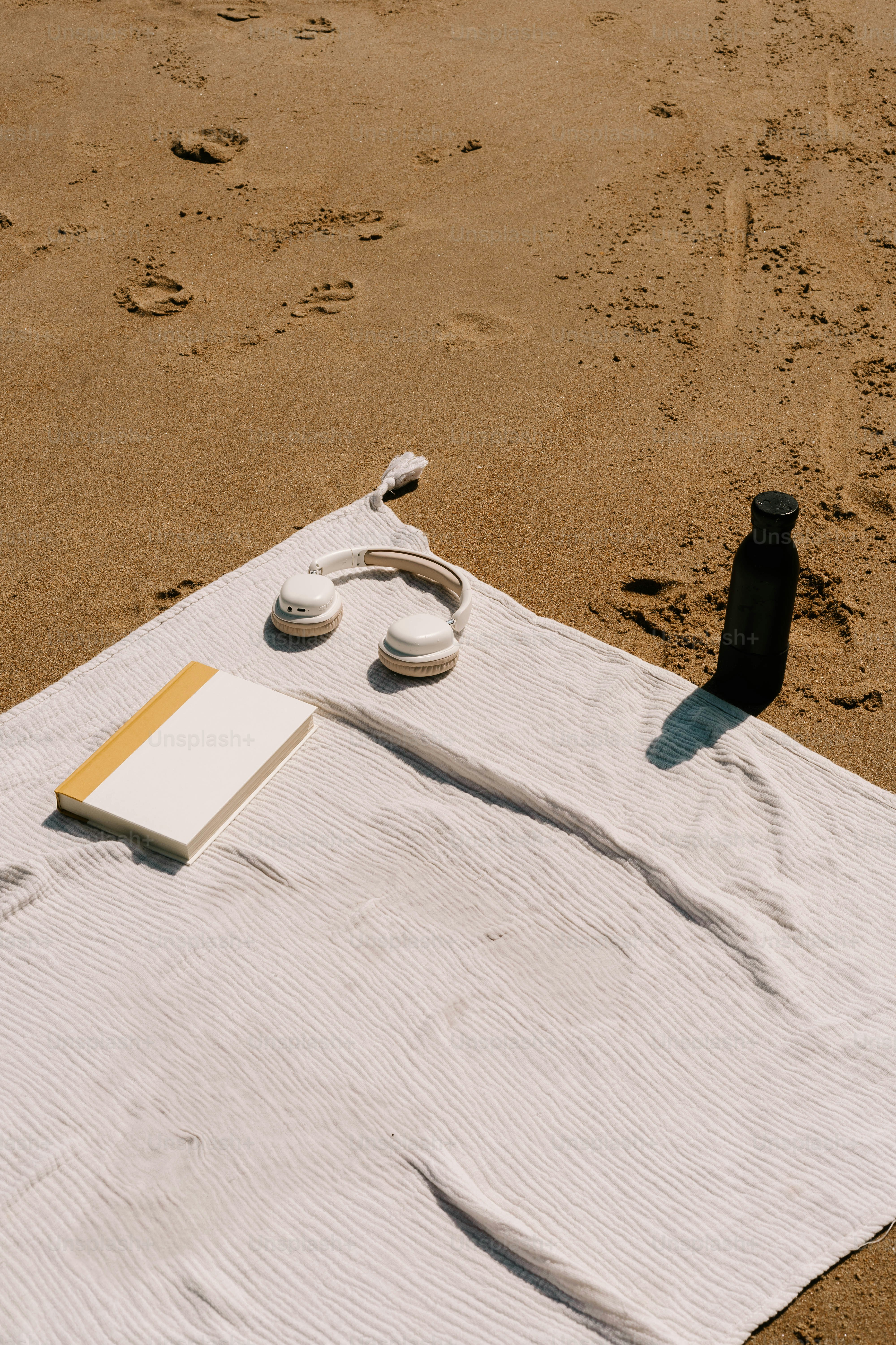 A towel, a book and a bottle on a beach