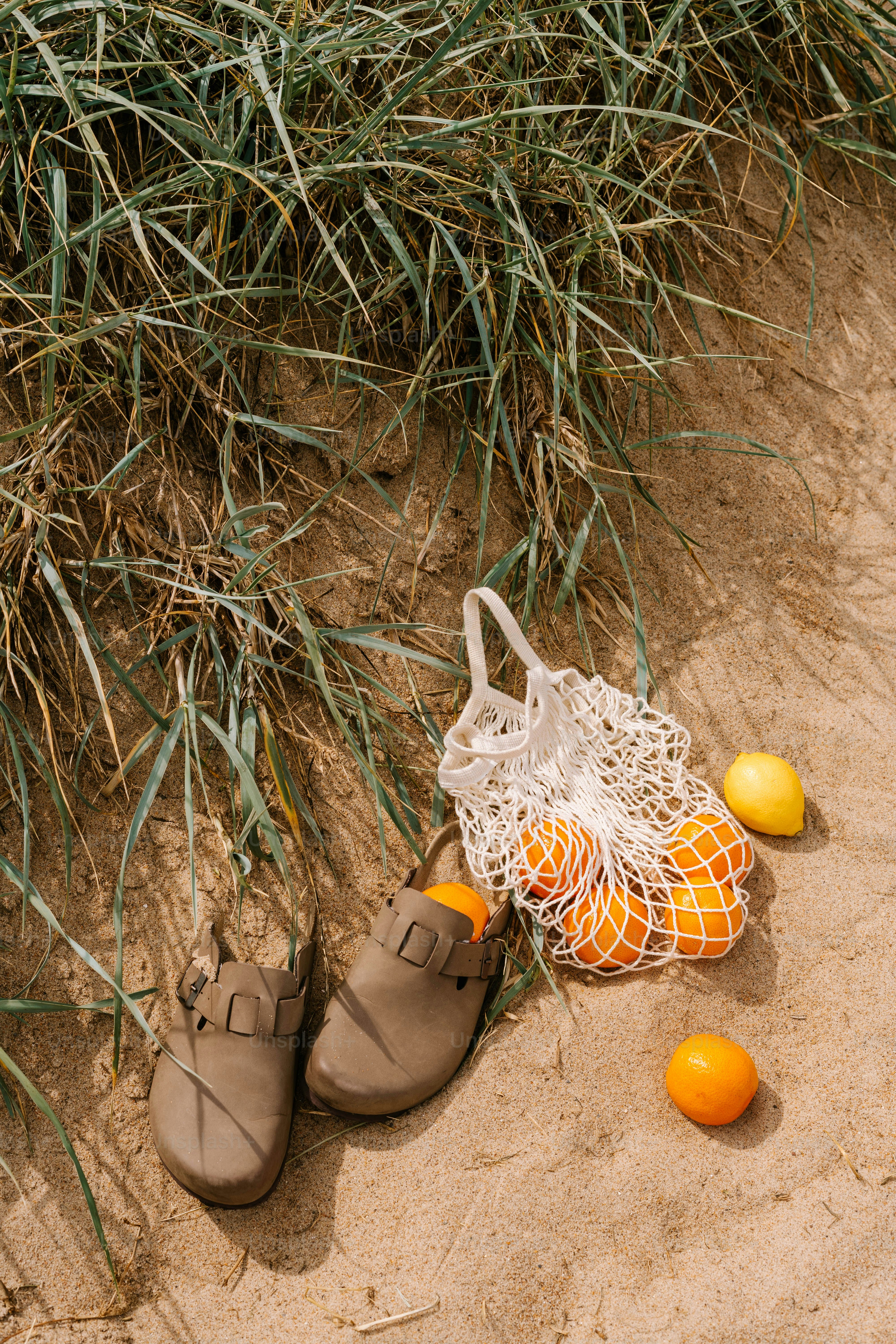 A pair of brown shoes sitting on top of a sandy beach