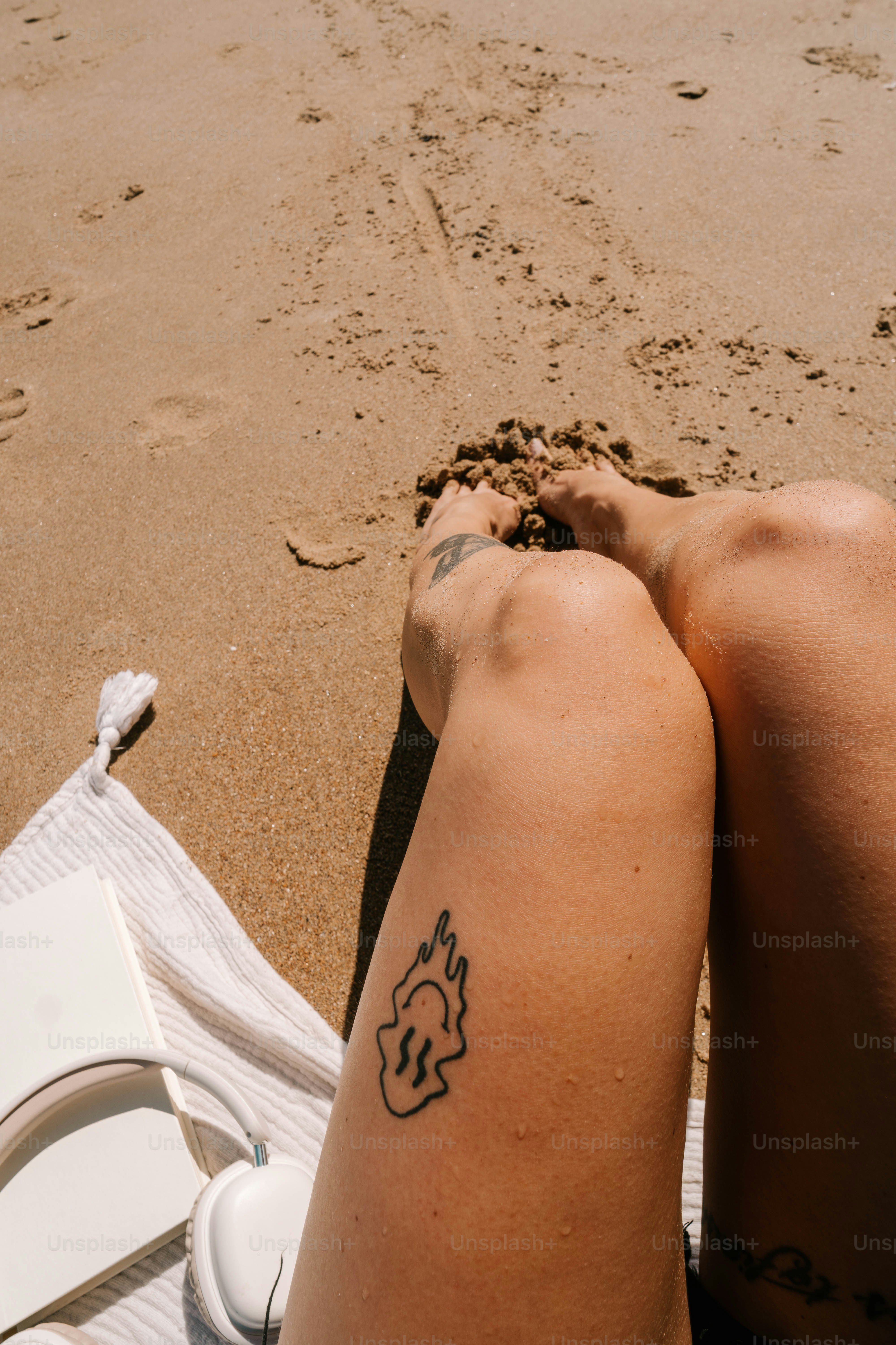 Una persona sentada sobre una toalla en la playa
