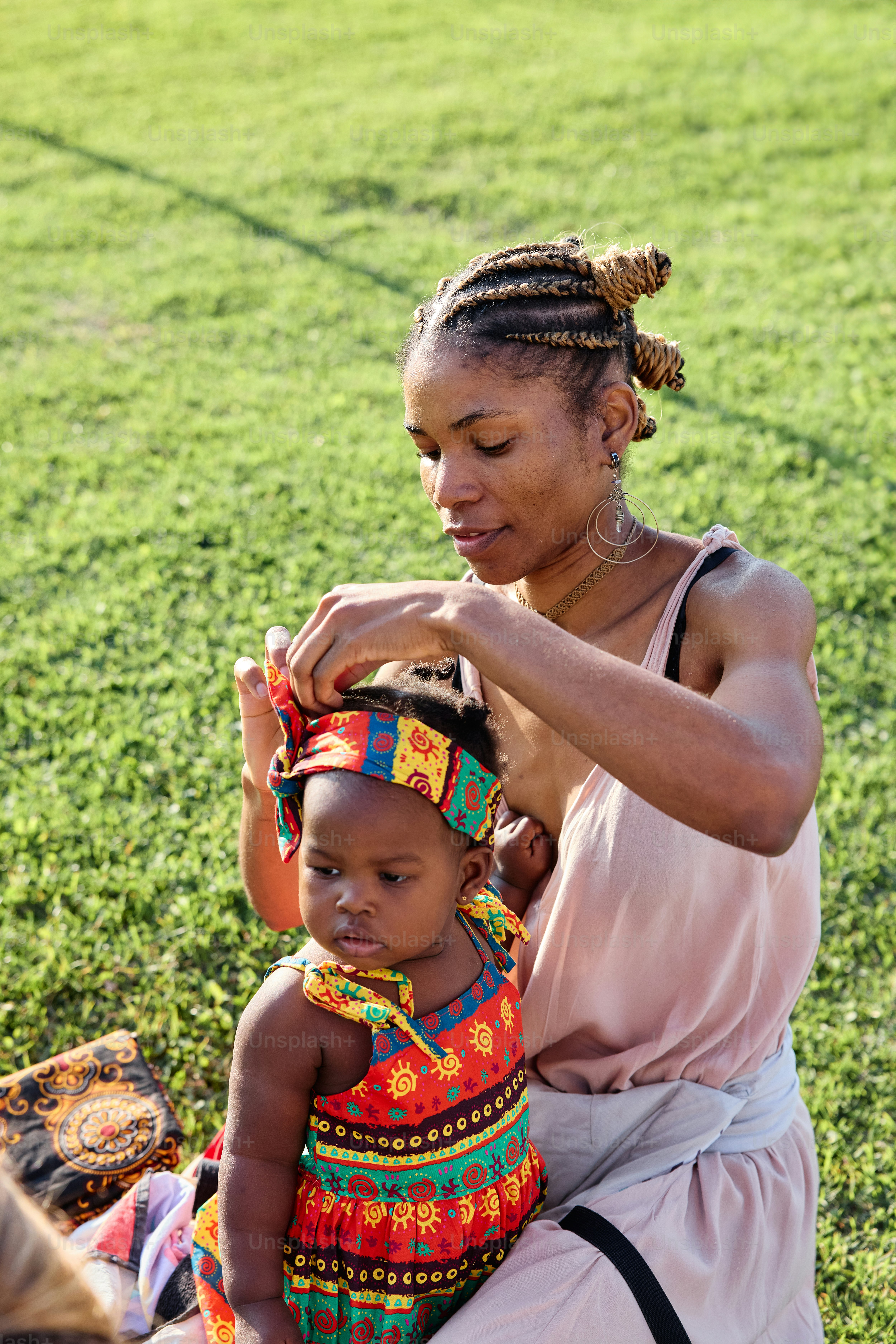 A woman combing a child's hair in a field