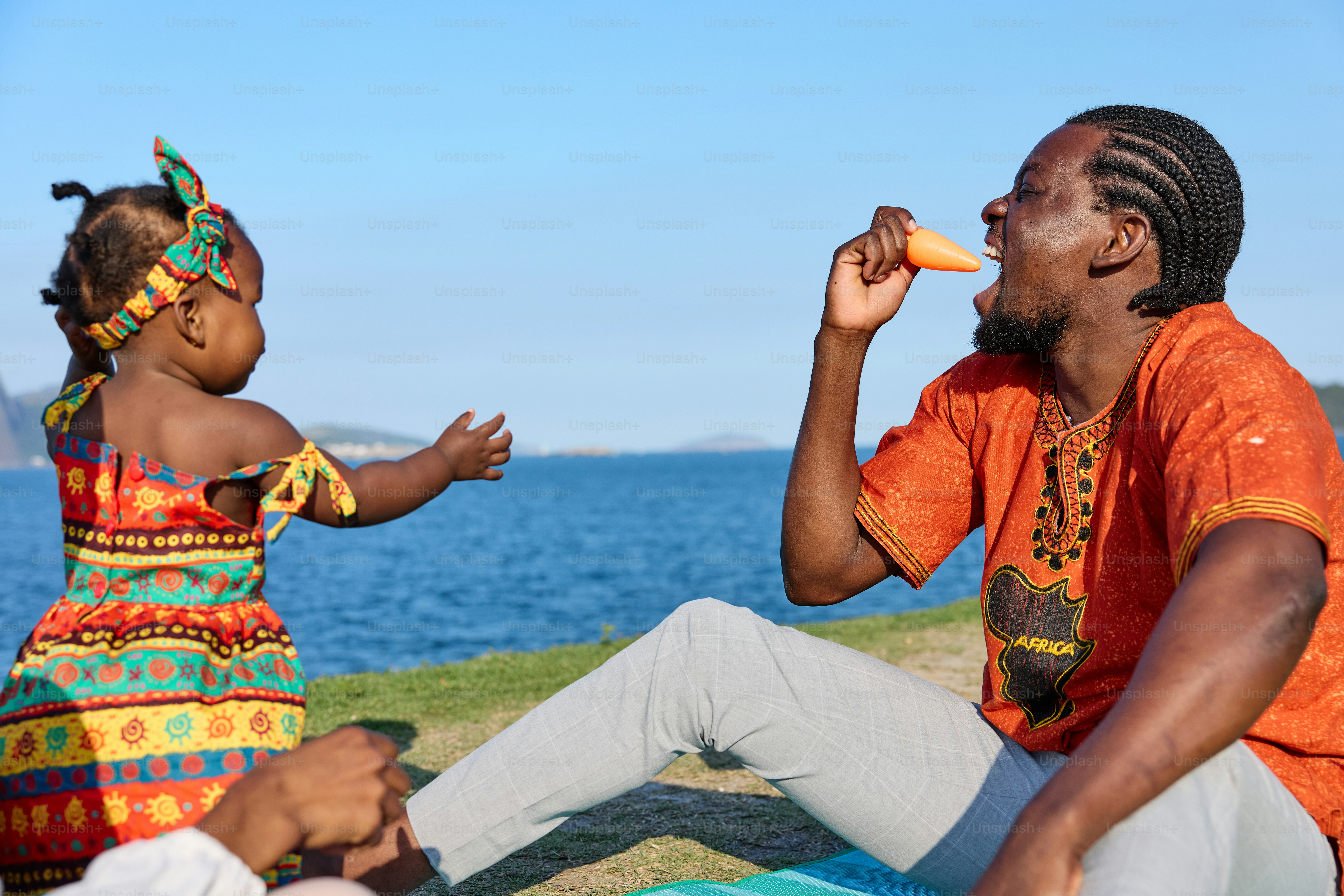 A man and a little girl sitting on a beach