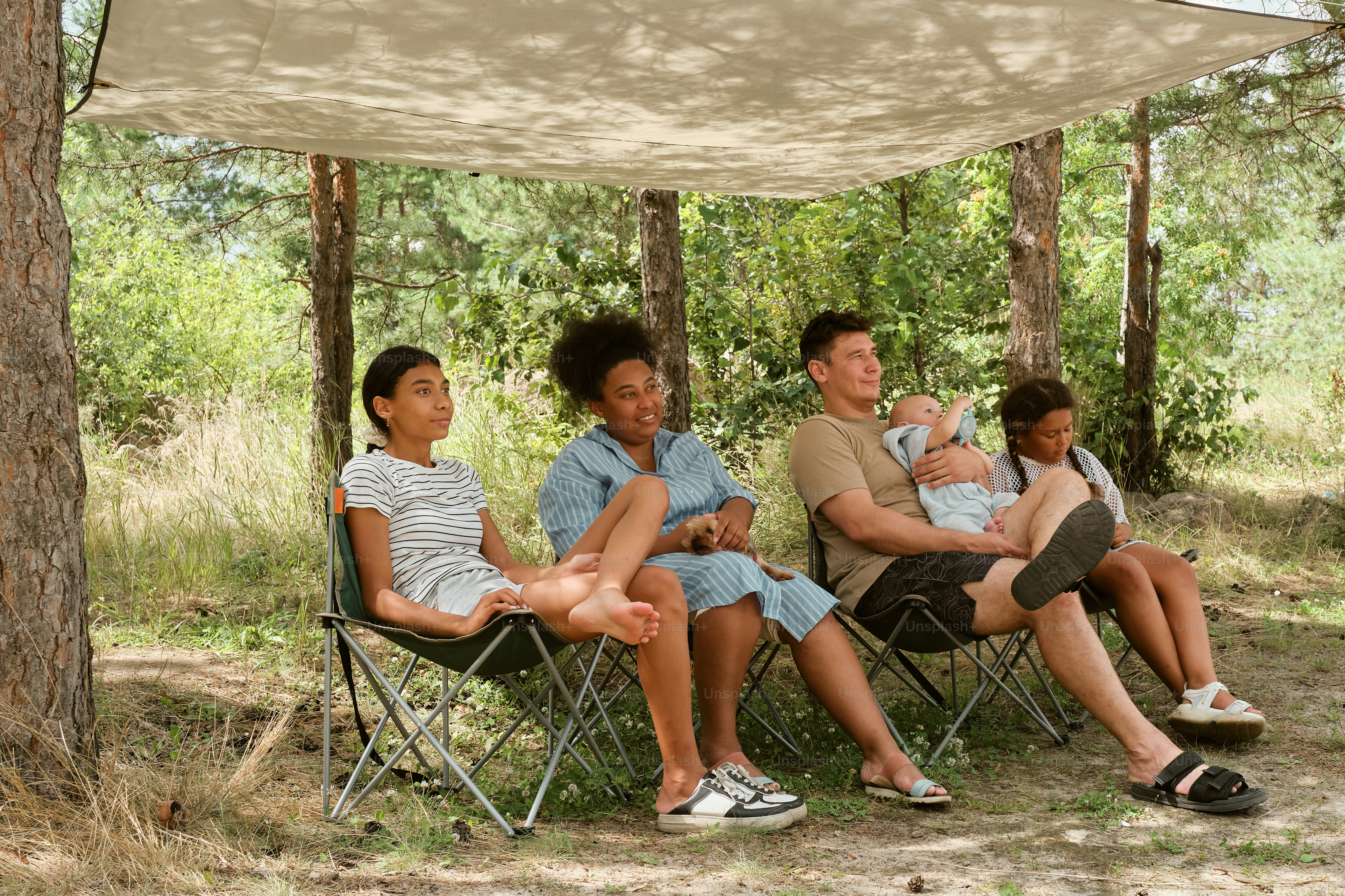 A group of people sitting under a tent in the woods