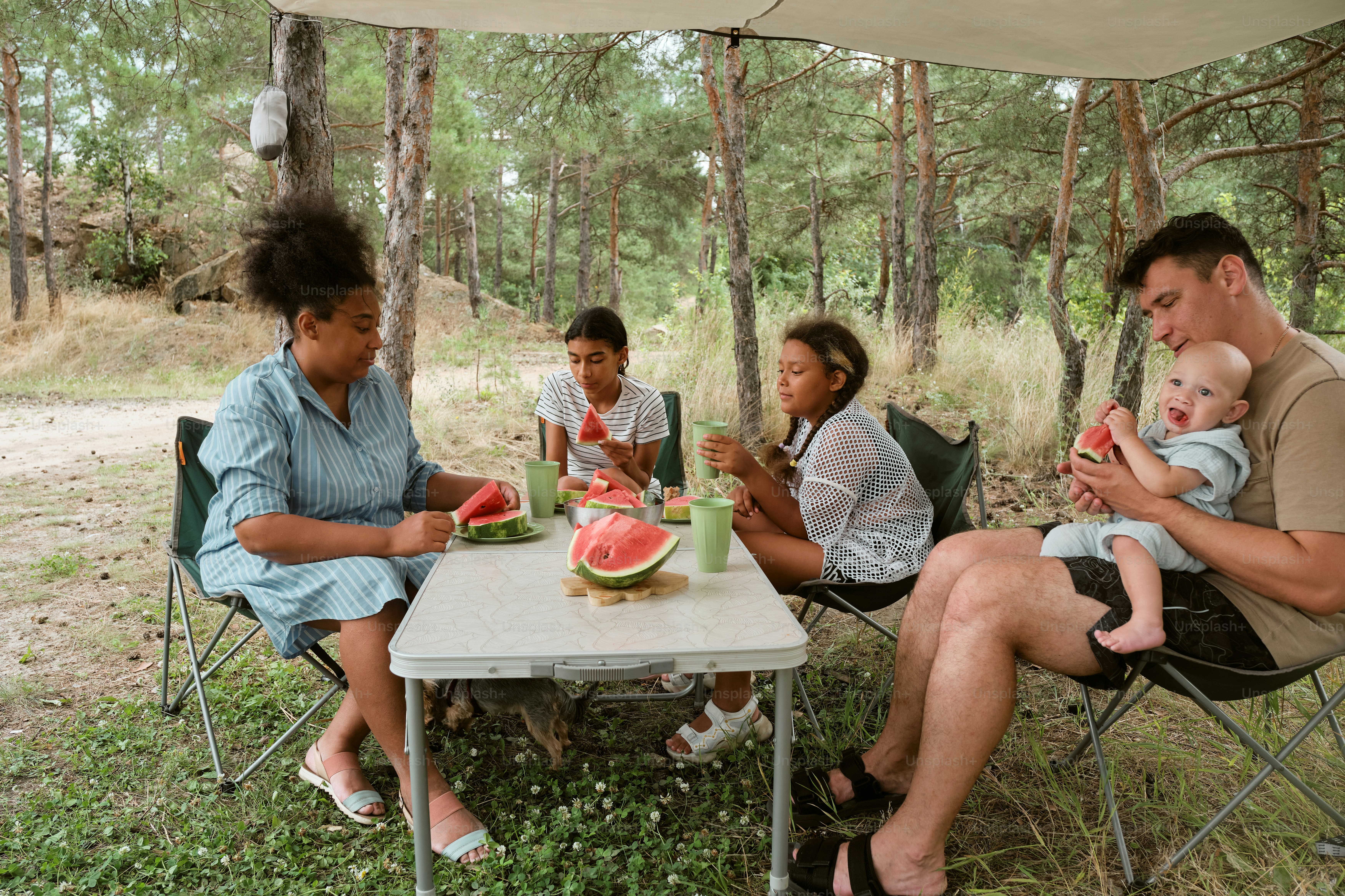 A group of people sitting around a table with watermelon slices on it